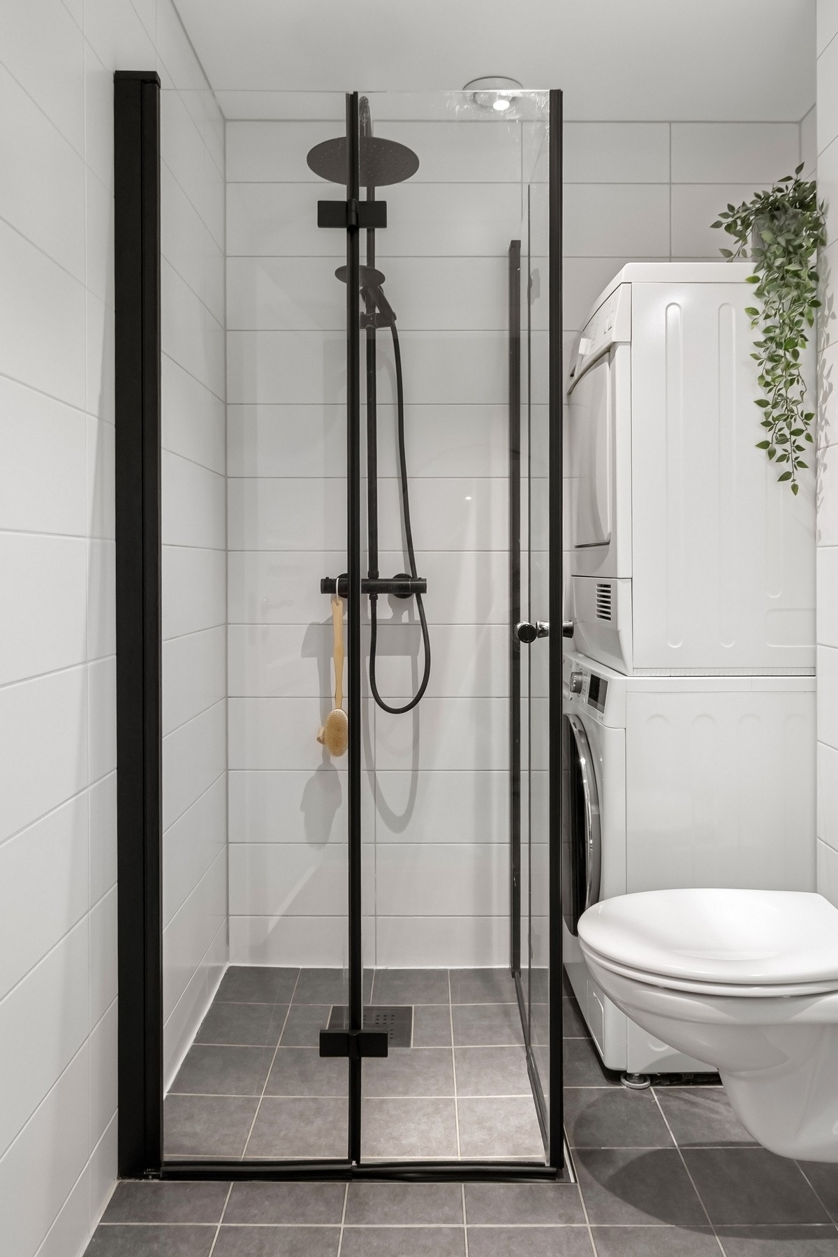 Badet er innredet med dusjhjørne, vegghengt toalett, servantseksjon med skuffer og speil med integrert lys. Galleribilde