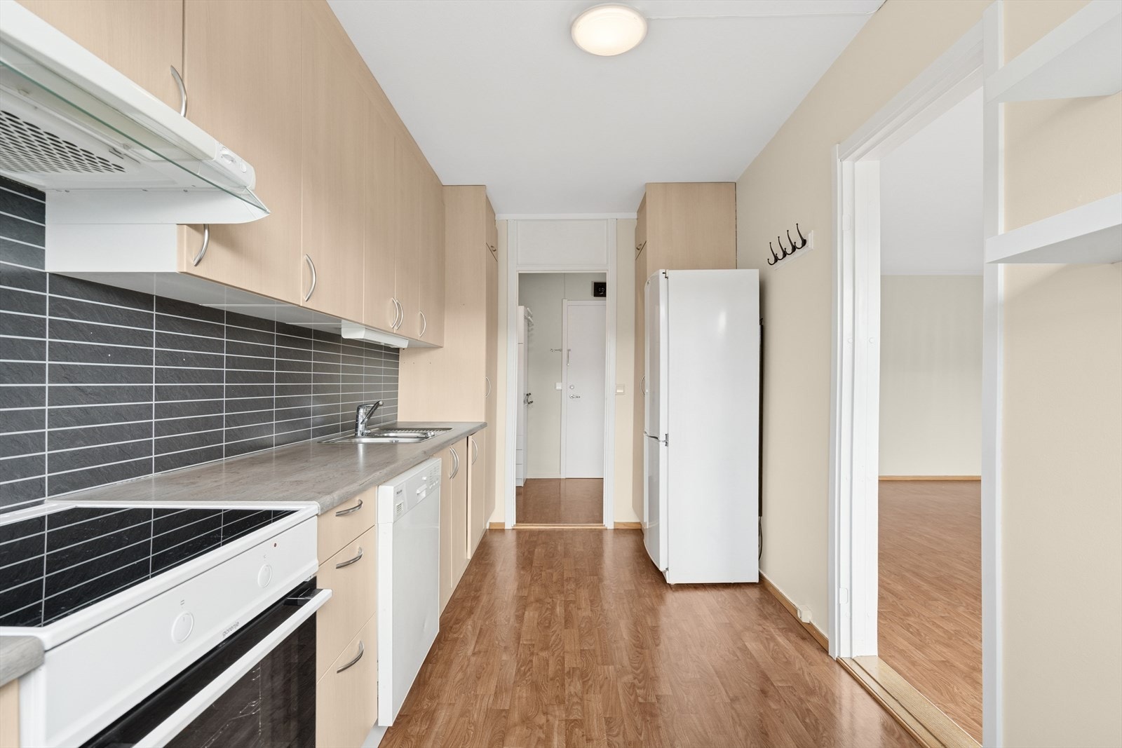 Kjøkkenet har en stilren innredning med folierte slette fronter, laminert benkeplate med nedfelt kjøkkenvask og Kitchenboard på vegg over benk Galleribilde