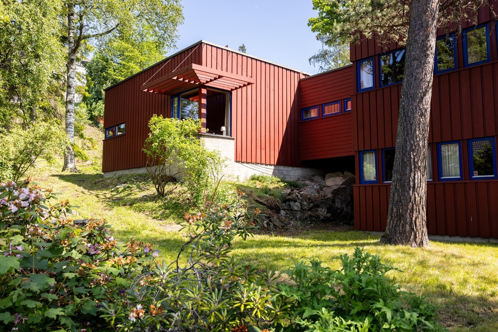 Tomten er pent opparbeidet med trær, busker og diverse beplantning. Galleribilde