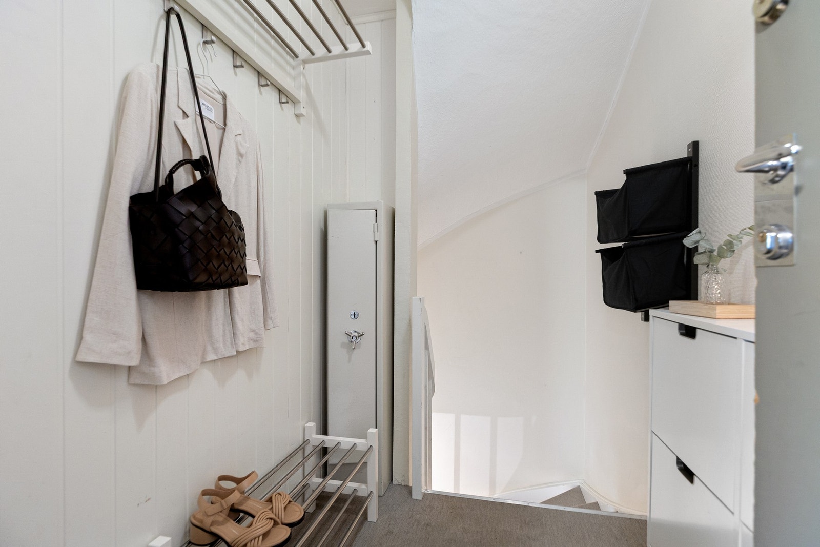 Her entrer du et lyst entré- og trapperom med teppebelagt gulv og plass for oppbevaringsløsninger. Galleribilde