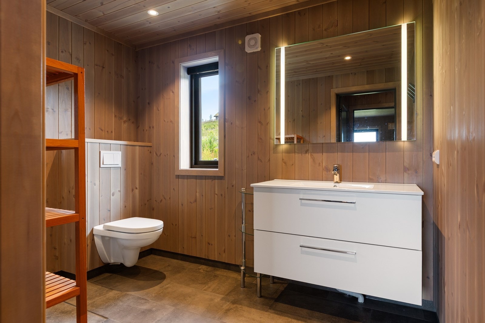 Badet har fliser med varme på gulv, og panel på vegg. Galleribilde