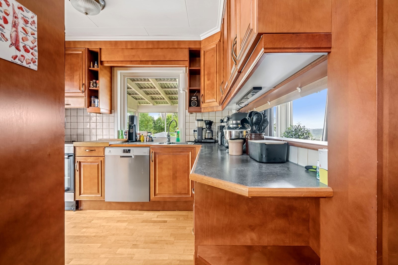 Kjøkkenet har en takhøy innredning med kirsebærbeisede fyllingsdører og fronter, samt en benkeplate i laminat. Galleribilde