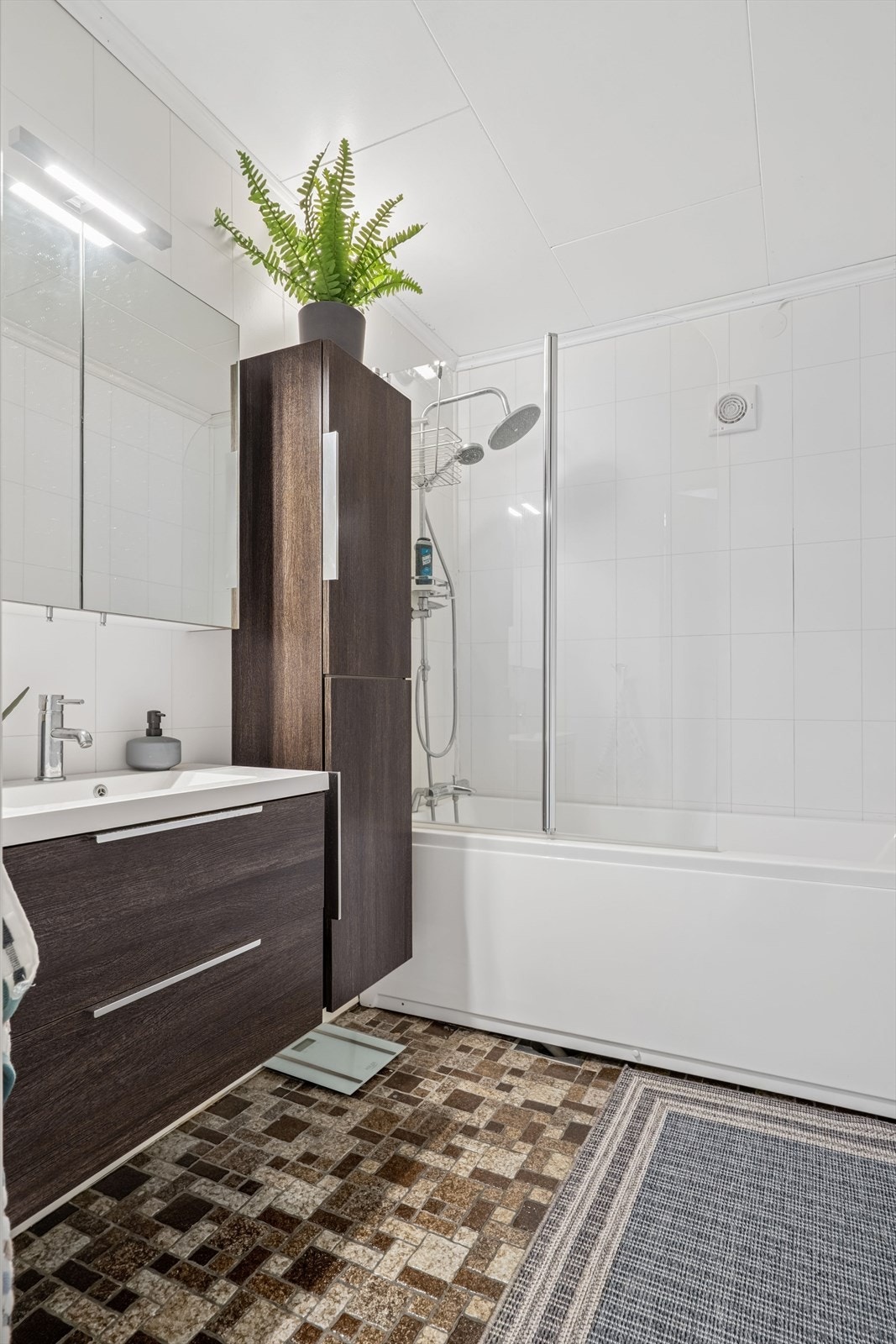 Baderommet ligger i 1. etasje og ble pusset opp i 2015. Badet er utstyrt med badekar, servantinnredning, speilskap og et praktisk høyskap. Det er eldre fliser på gulv (gulvvarme) Galleribilde