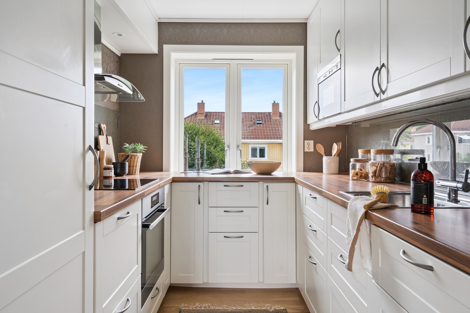 Stilrent kjøkken med integrerte hvitevarer som kjøl/fryseskap, stekeovn, platetopp, oppvaskmaskin og mikrobølgeovn. Galleribilde