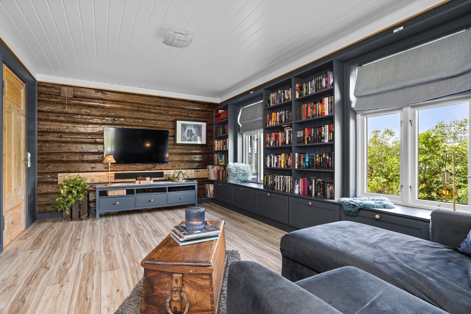 Langs den ene veggen har stuen en flott, plassbygget hylleløsning med skuffer, utmerket for bøker, planter og annen dekor Galleribilde