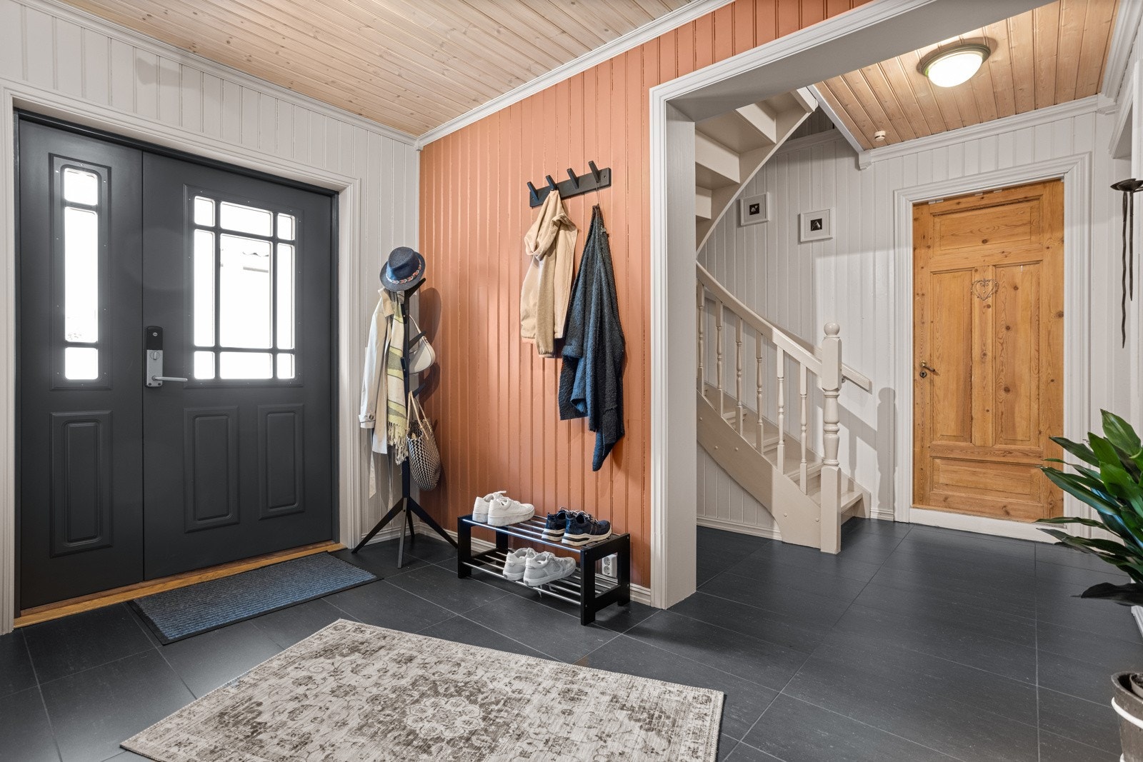 Villaen har en innbydende hall med store, mørke gulvfliser og panelvegger malt i tidsriktige farger i 2024 Galleribilde