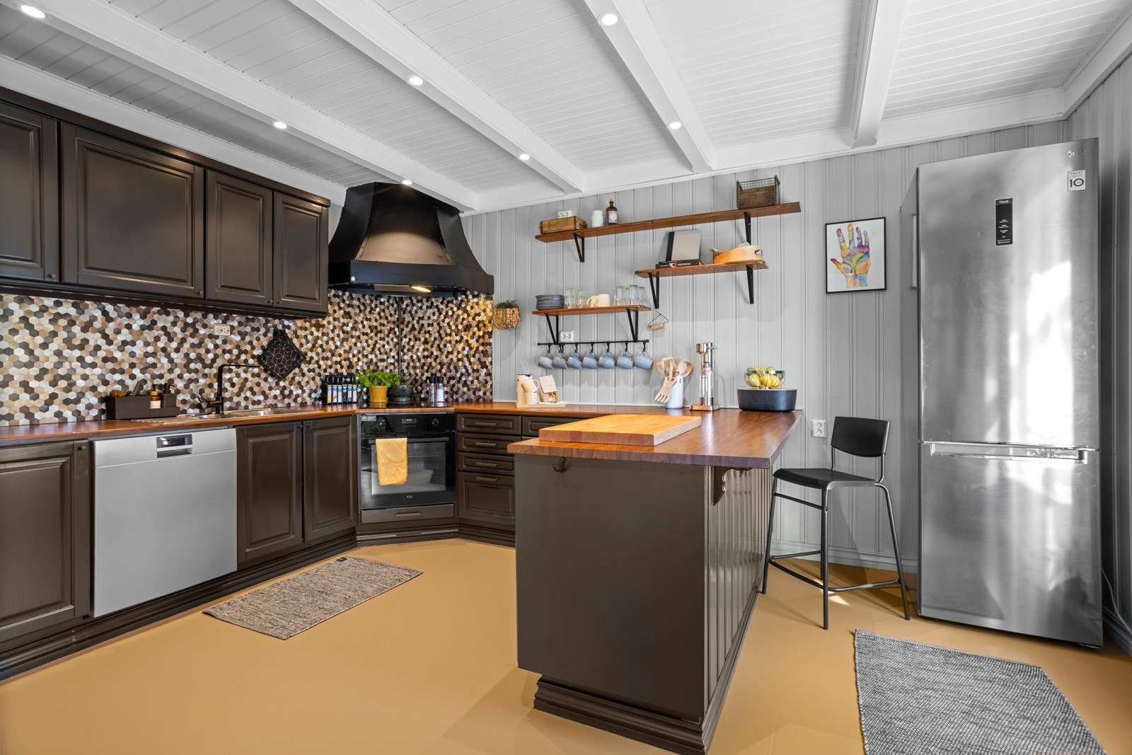 Kjøkkenet er hjertet i huset, med malt laminat på gulvet og panelvegger malt i lysegrått i 2021 Galleribilde