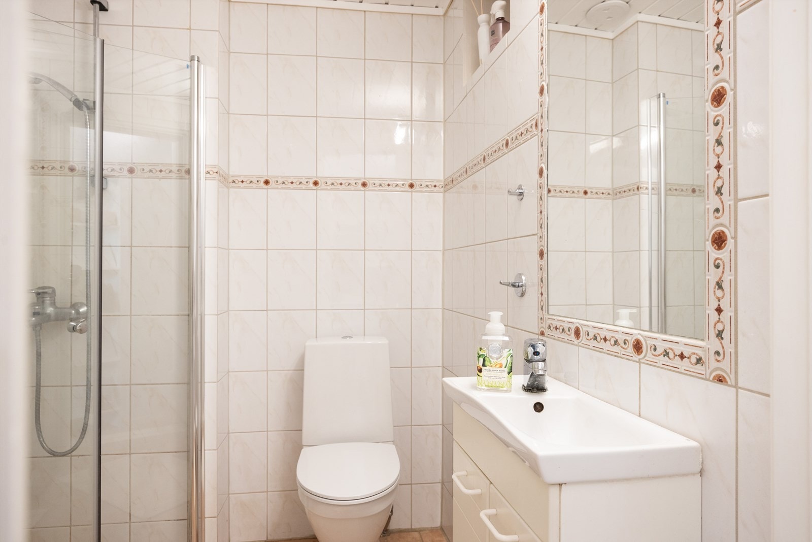 Badet er innredet med klosett, servant nedfelt i innredning, speil og dusjhjørne med svingbare glassdører. Videre er det opplegg for vaskemaskin. Galleribilde