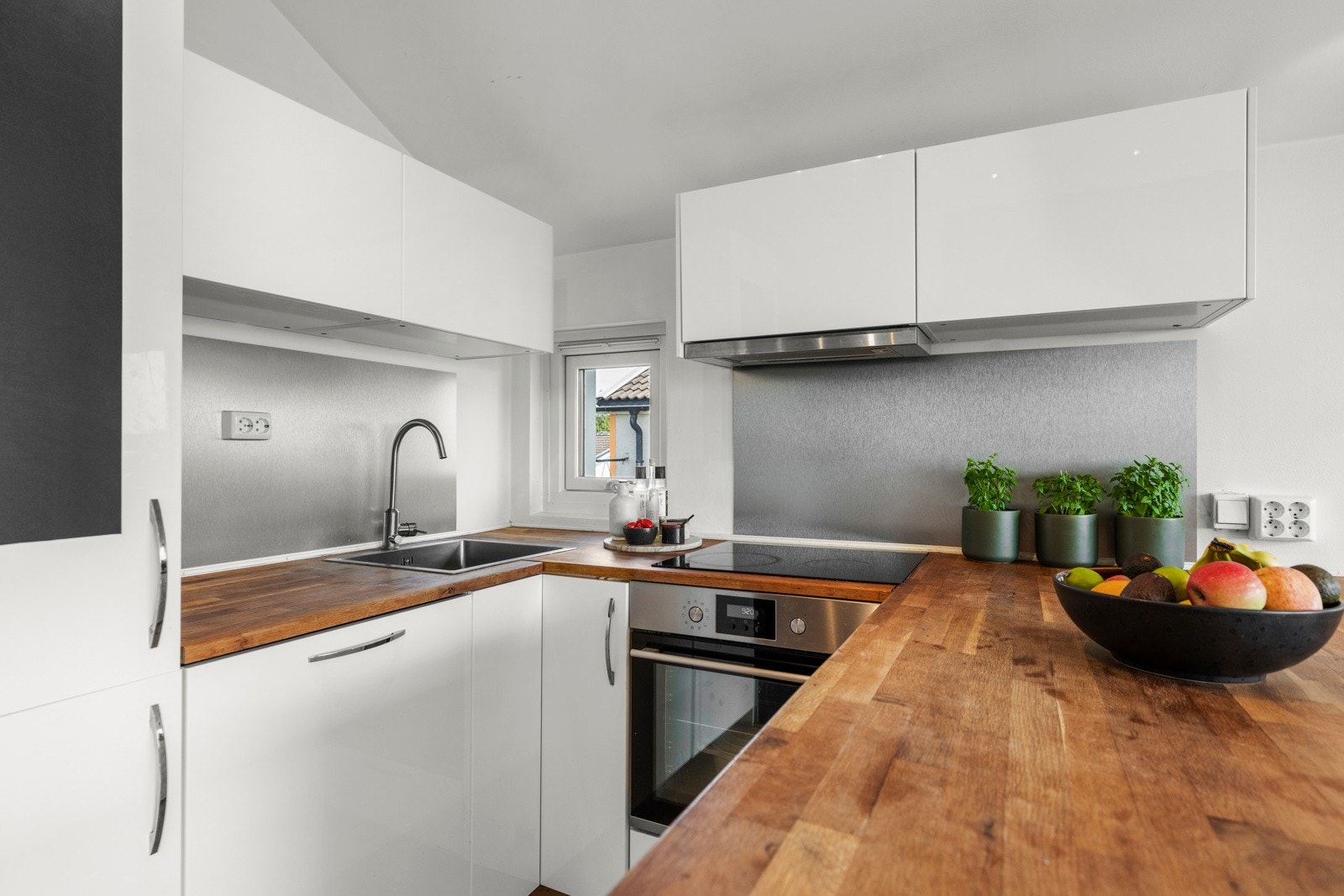 Kjøkkenet er utstyrt med integrerte hvitevarer, inkludert platetopp, komfyr, oppvaskmaskin og kombinert kjøl/frys Galleribilde