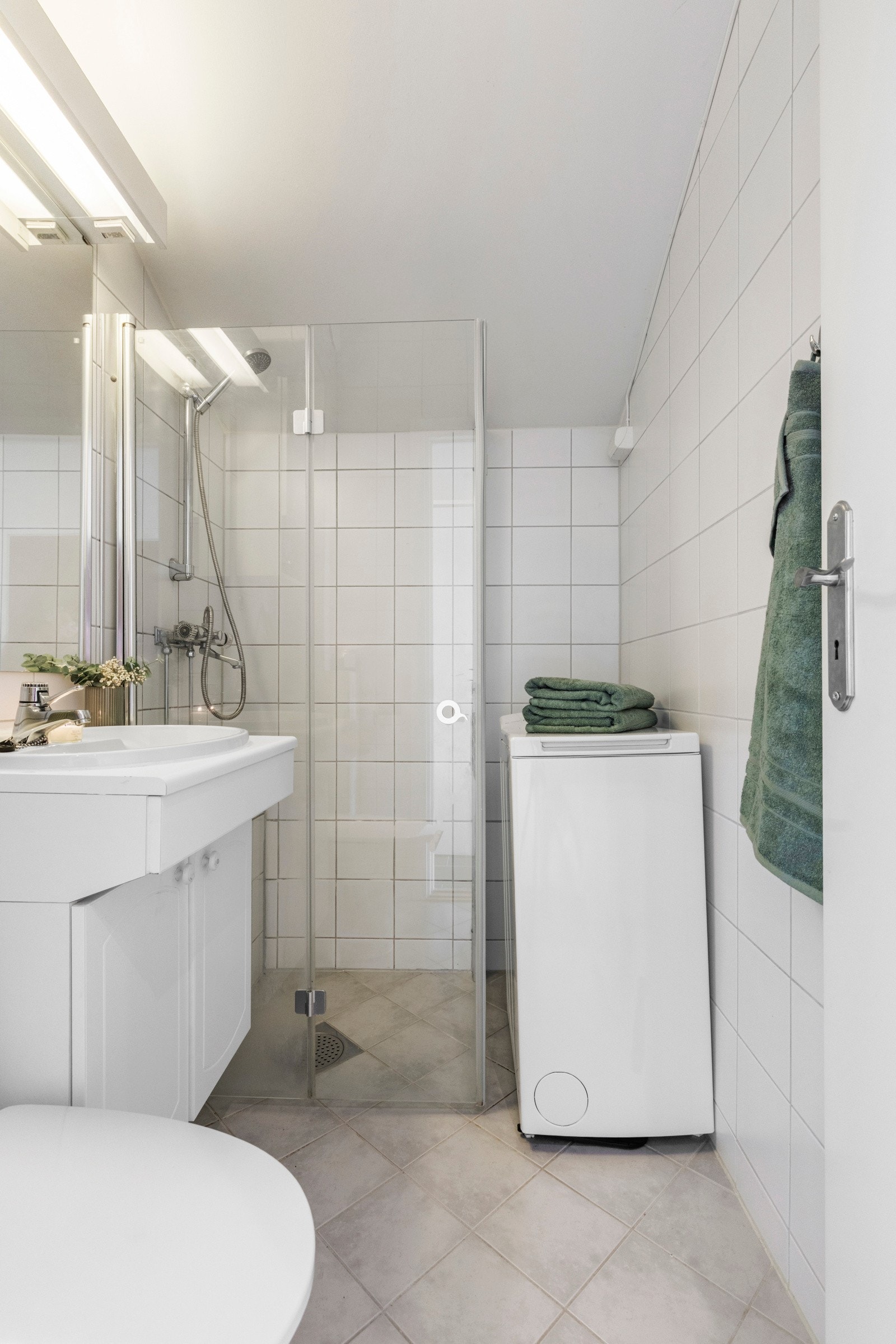 Rommet er utstyrt med dusjhjørne, gulvstående toalett og en innredning med nedfelt servant, samt opplegg for vaskemaskin Galleribilde