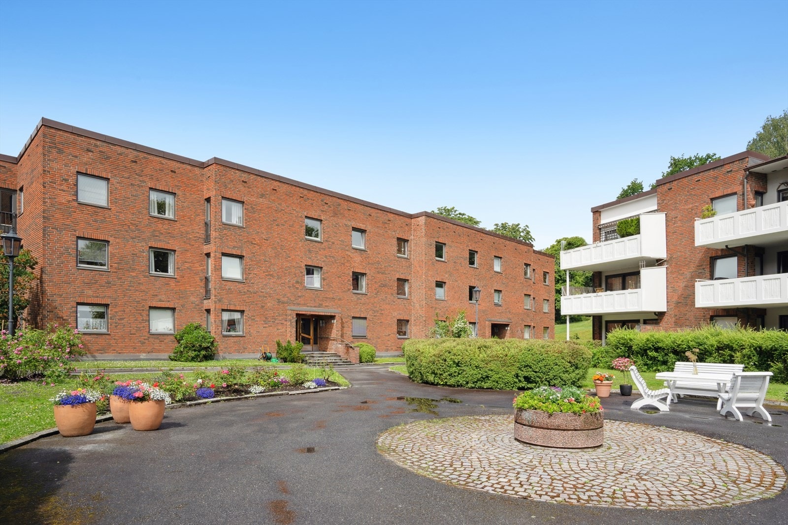 Pent opparbeidet fellestomt med gressplen, asfalterte internveier, benker, belysning og diverse beplantning. Galleribilde