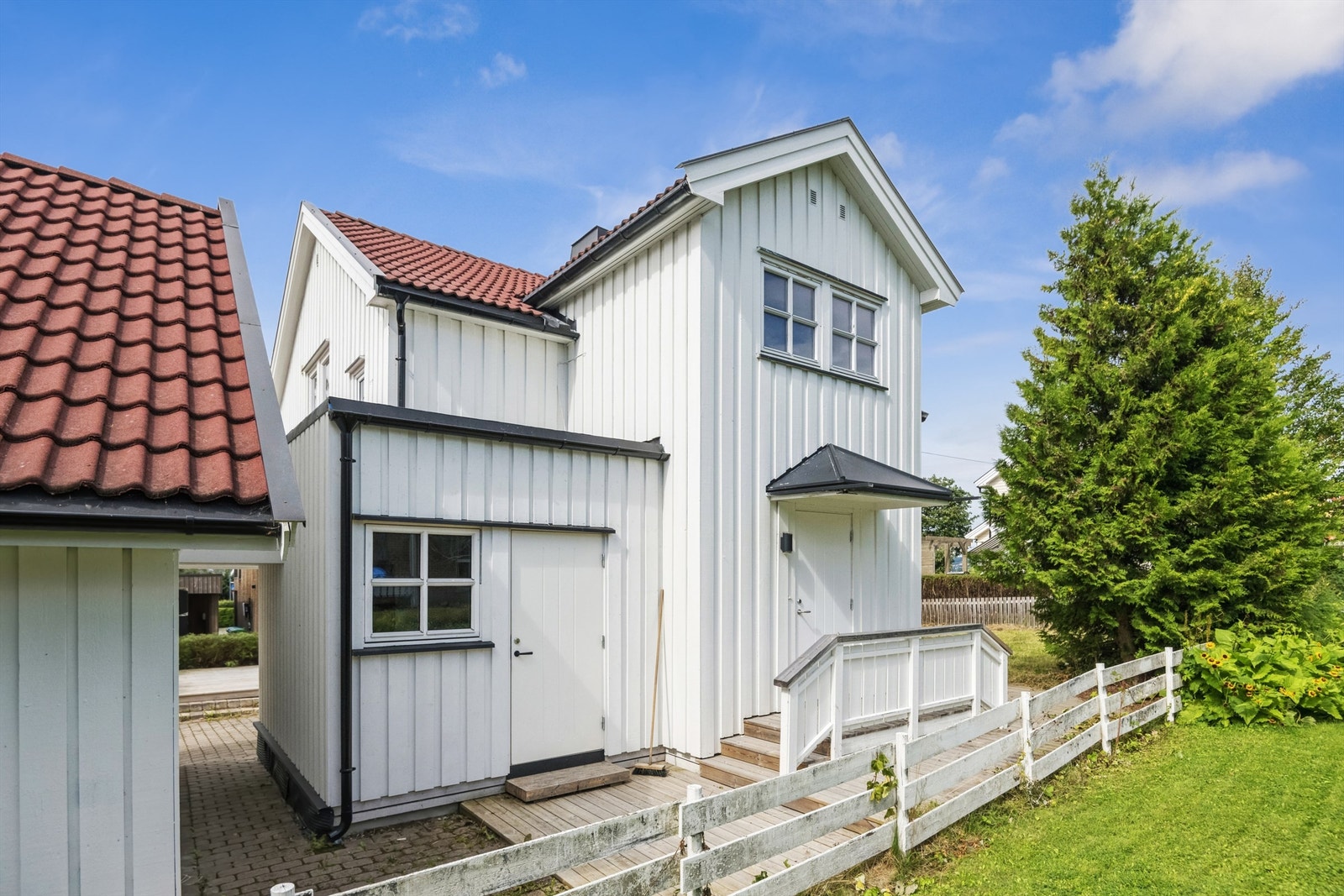 Adkomst til kjellerleilighet via egen ytterdør, og til hoveddelen av huset like bortenfor, via overbygget inngangsparti. Galleribilde