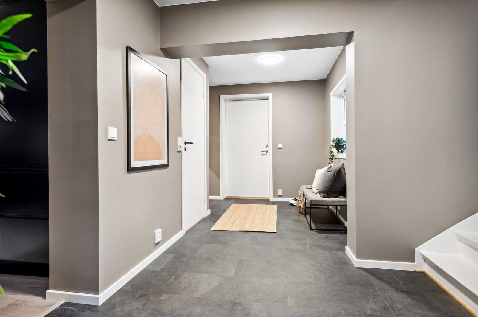 Velkommen inn! Entré med god plass til garderobe og direkte tilgang til hovedetasjen. Bildet avviker noe fra nåsituasjon. Det er etablert dør til høyre i bildet der krakk under vindu står, til påbygget inngangsparti til kjellerleiligheten. Galleribilde