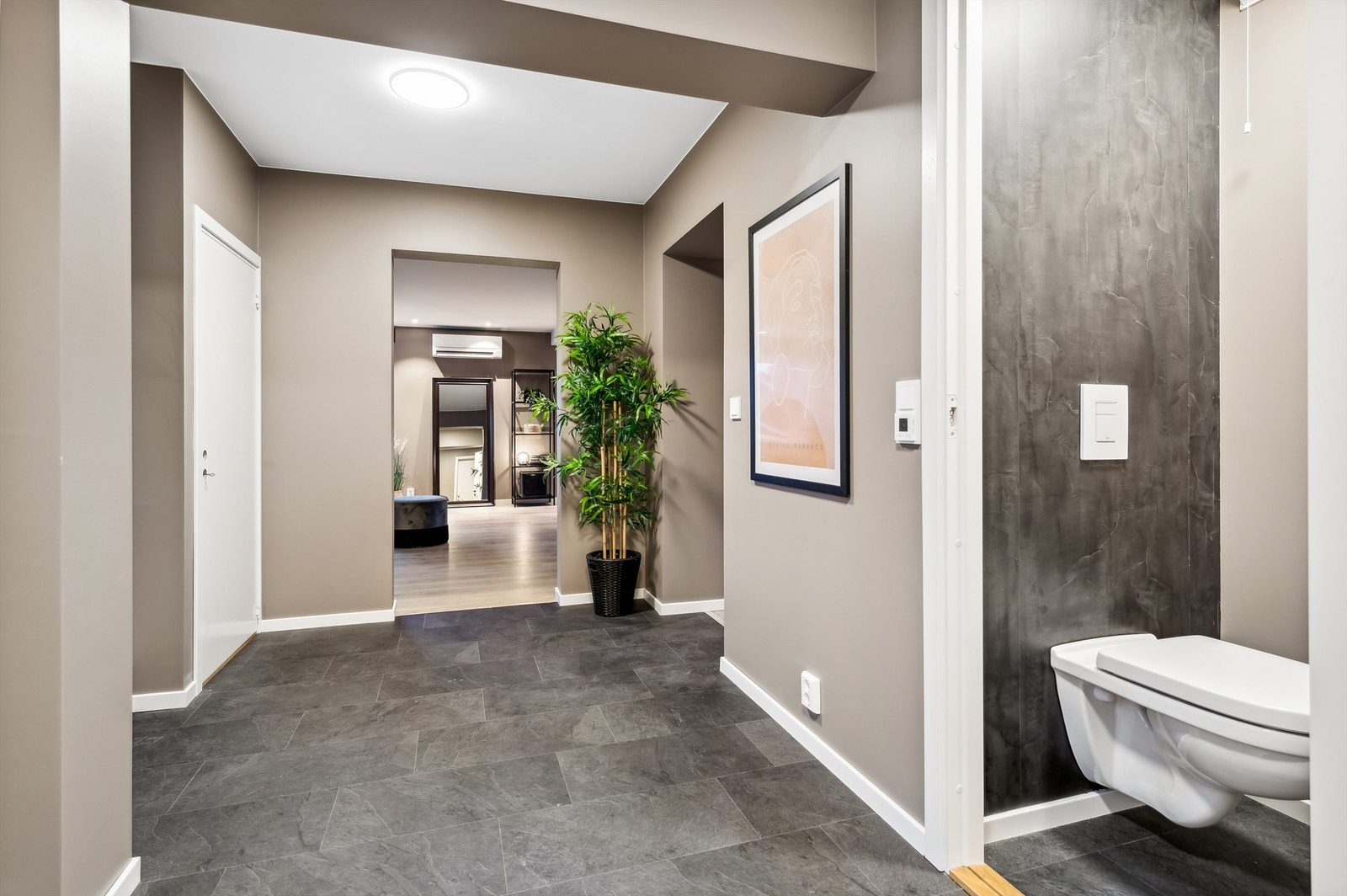 Oversiktlig hall med flislagt gulv og adkomst til toalettrom og stue. Galleribilde