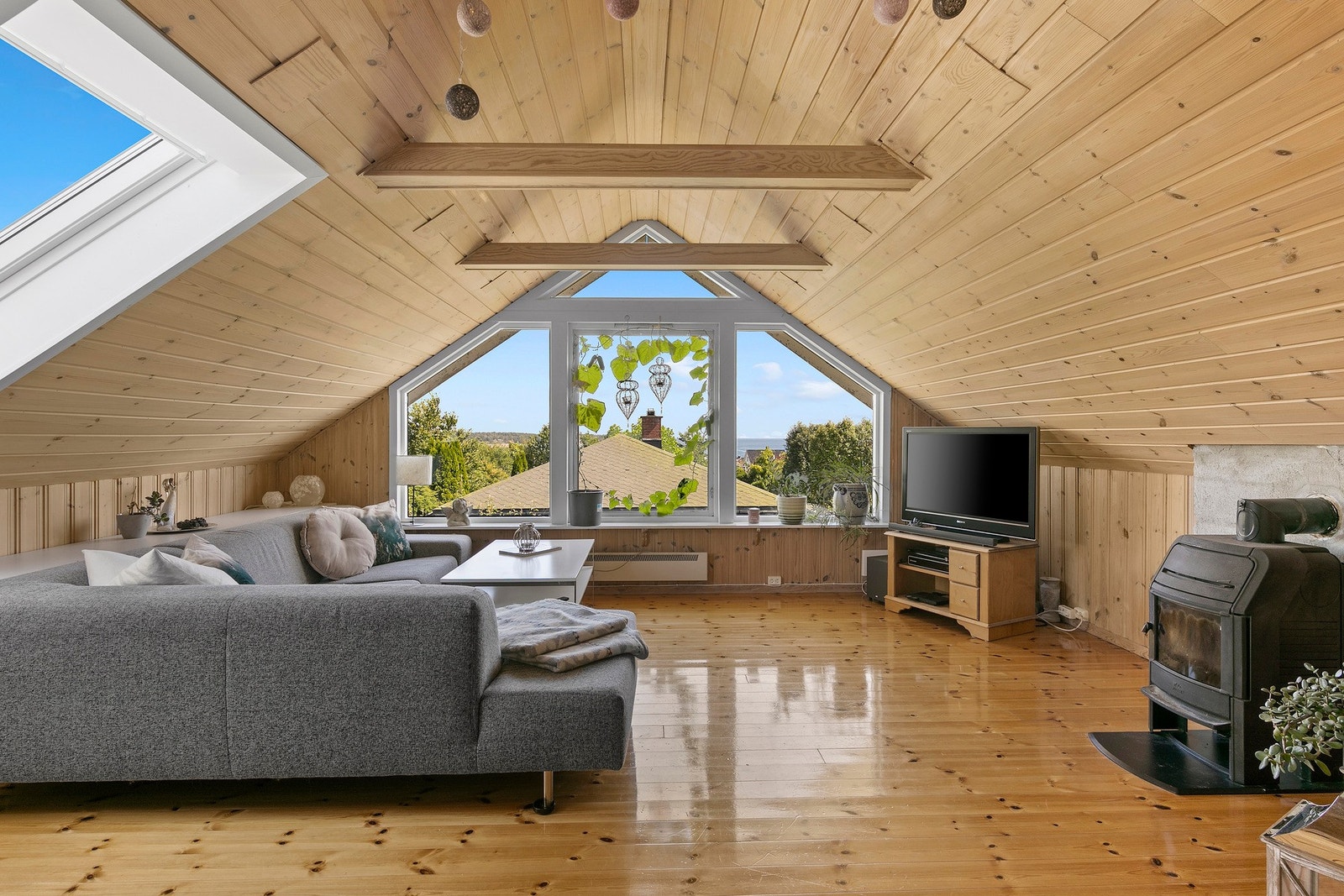 I andre etasje er det en romslig og pen stue med luftig atmosfære. Dette understrekes med dagslyset som strømmer inn via store vinduer, og utsikten fra endeveggen er langstrakt og idyllisk. Stuen har naturlig panel på veggene og i himlingen, lakkert, orig Galleribilde