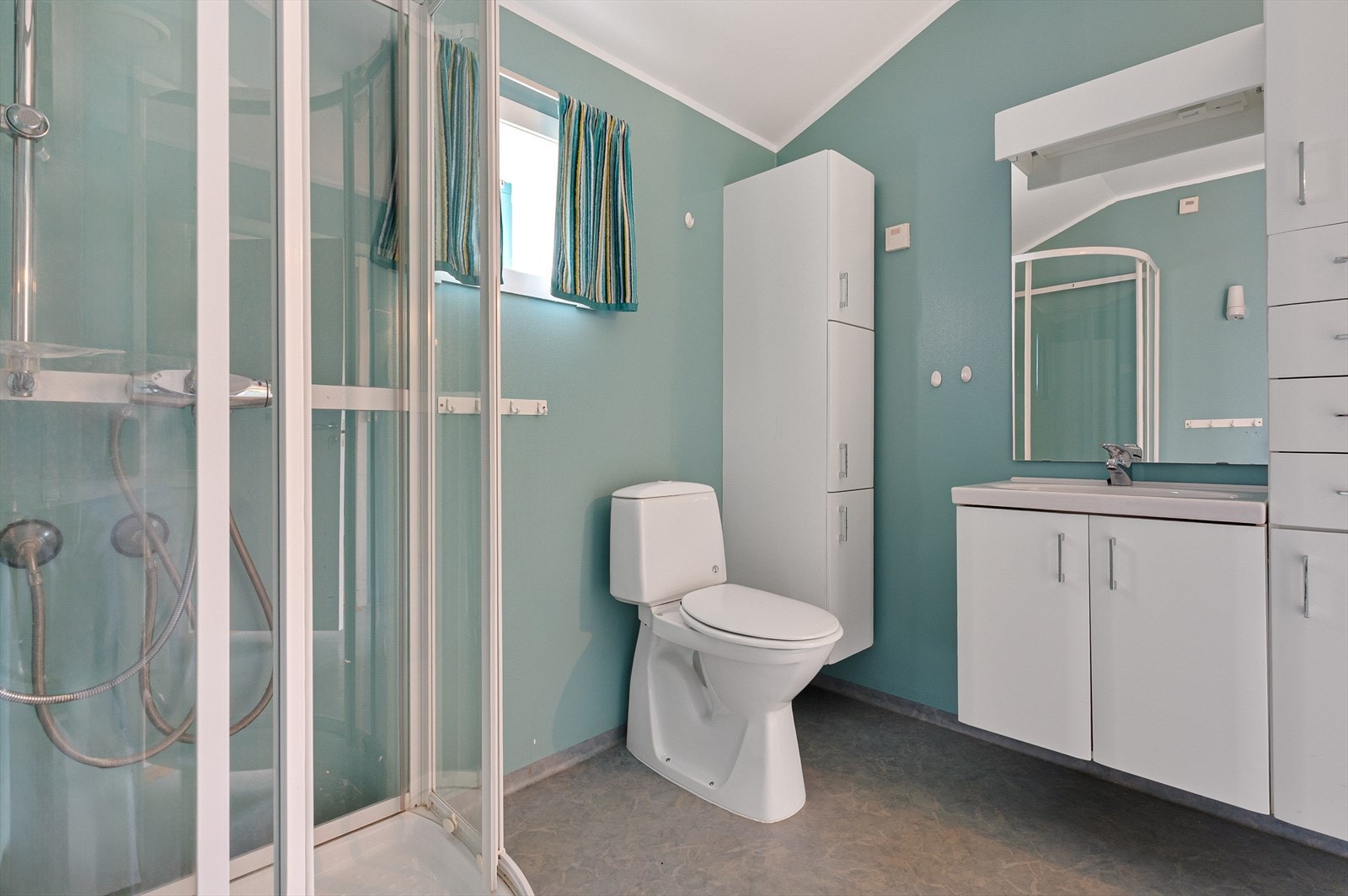 Badet er innredet med baderomsinnredning med servant, toalett og dusjkabinett. Galleribilde
