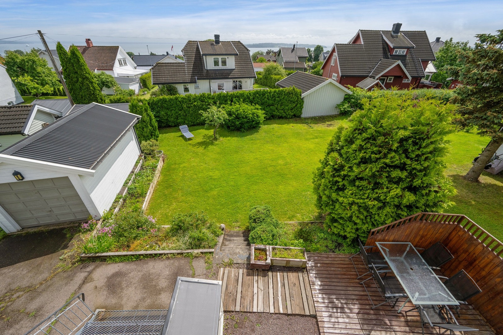 Utsikt fra verandaen og ned mot hagen og garasjen Galleribilde