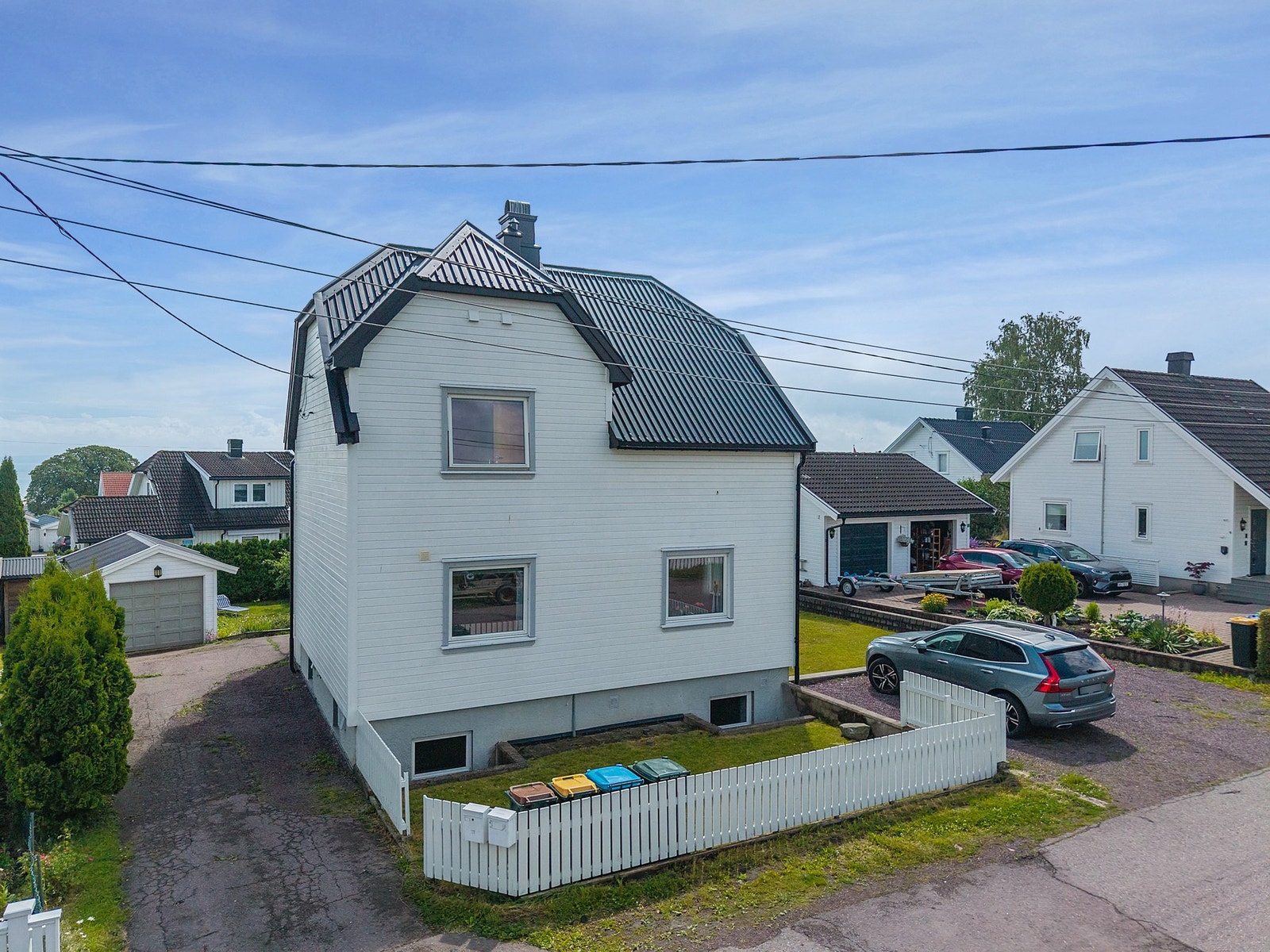 Her ser vi fasaden mot veien og med biloppstillingsplass for leieboer/gjester Galleribilde