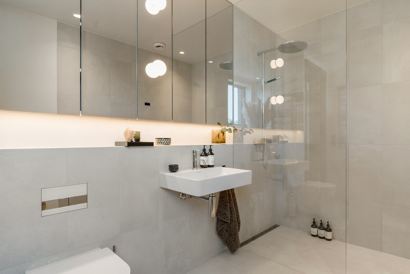 Begge badene er innredet med speilskap helt opp til himlingen og det er satt inn Flos-lamper på speil både på badene og på toalettet Galleribilde