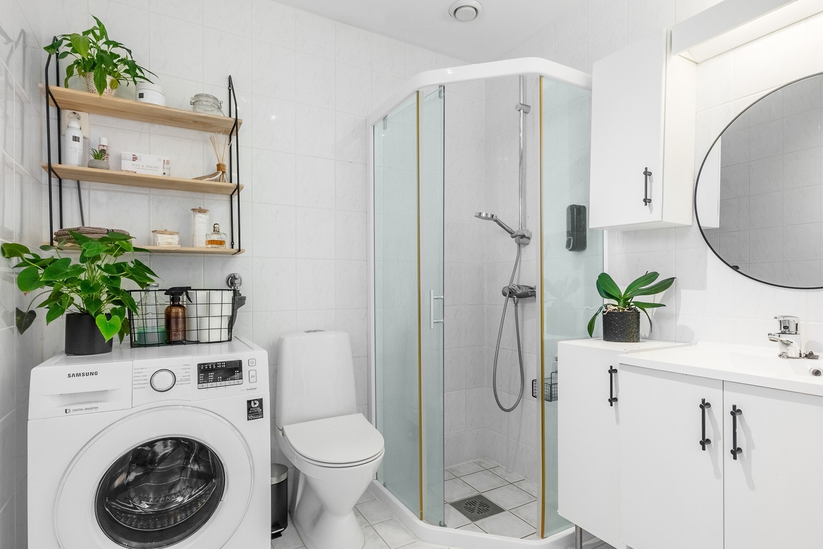 Badet er fra byggeår med hvite, flislagte overflater, varmekabler og tidløs innredning med god oppbevaringsplass. Videre er det dusjhjørne med kabinettdører, toalett og opplegg for vaskemaskin. Galleribilde