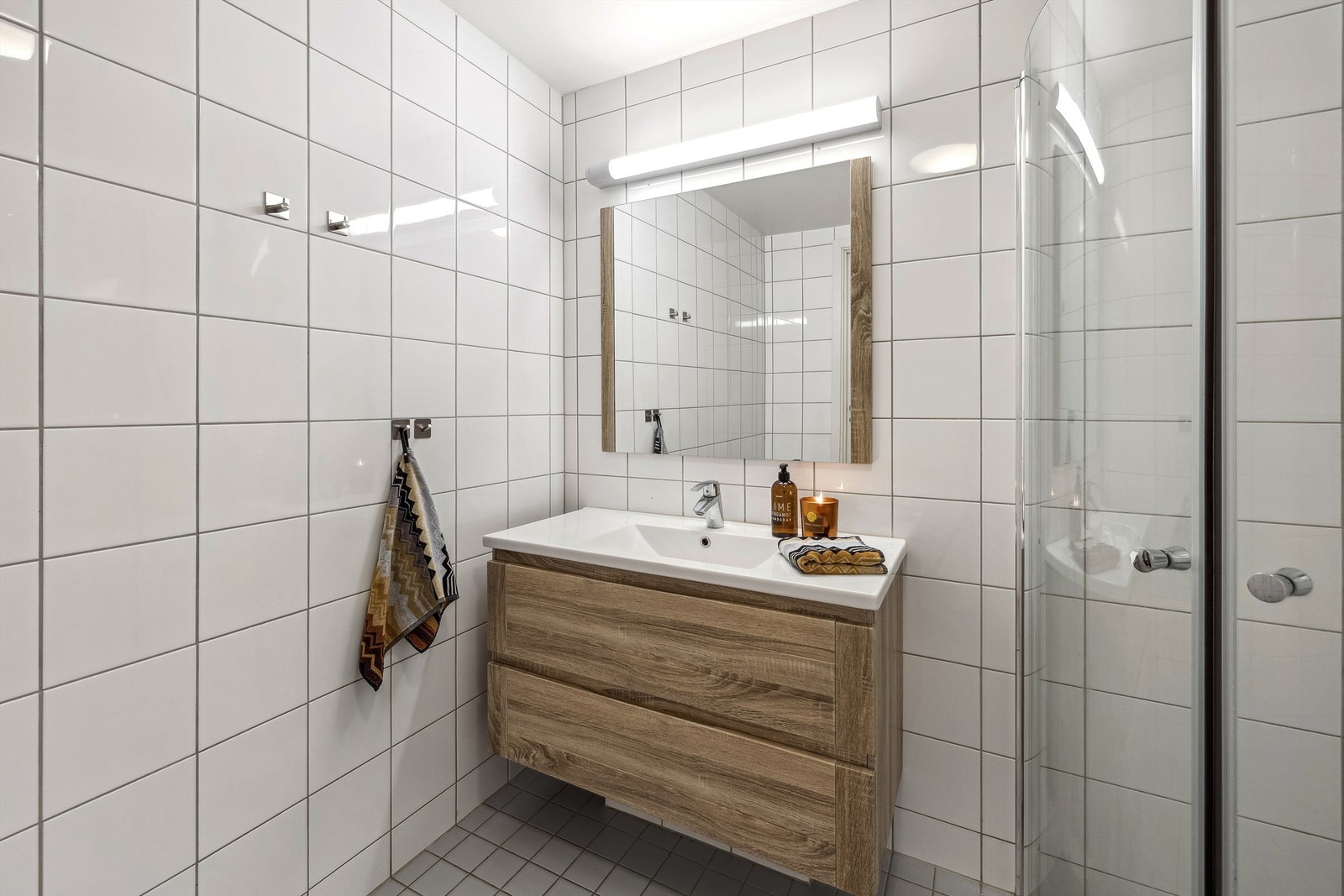 Badet har flislagte overflater, vegghengt toalett og romslig servantinnredning. Galleribilde