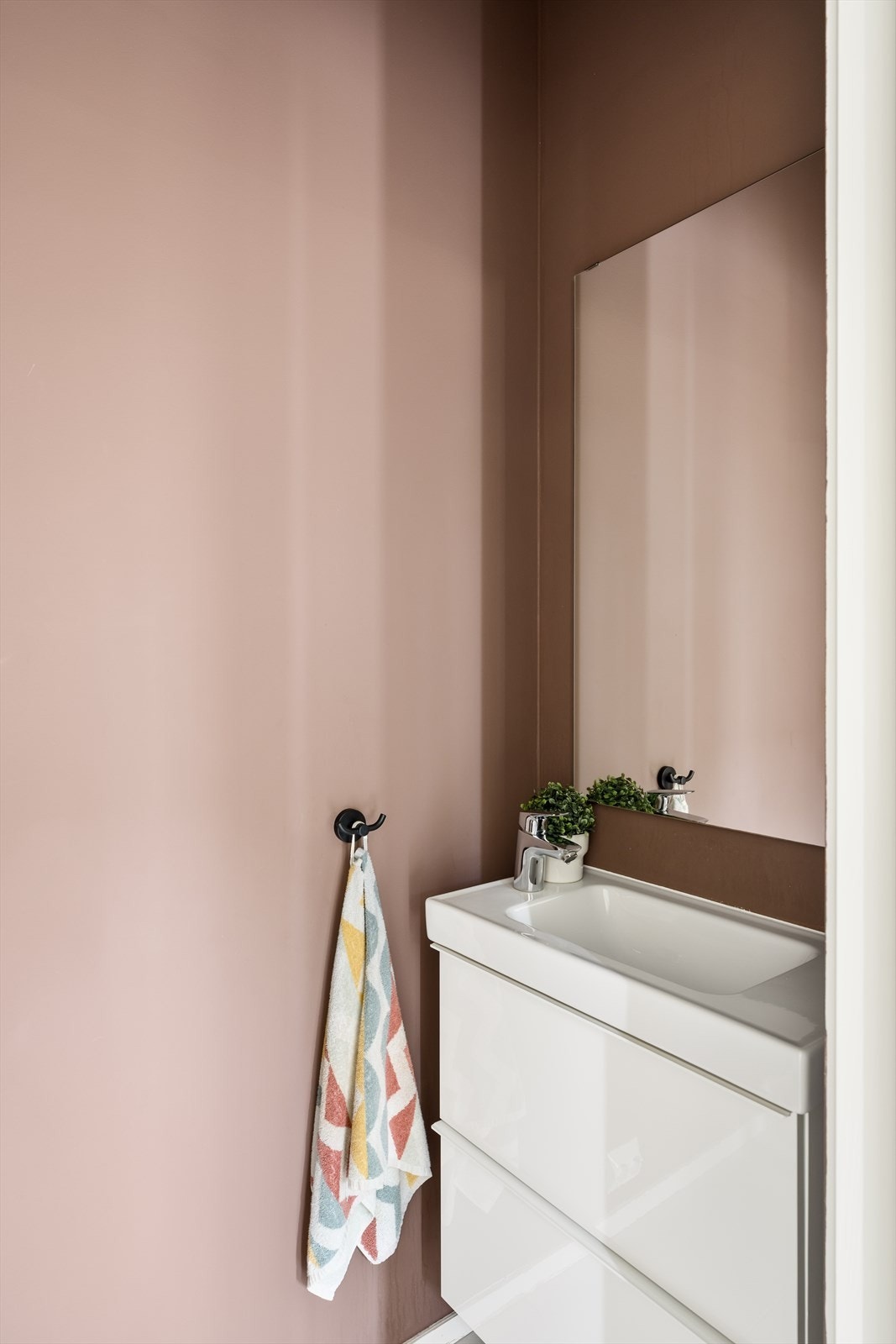 Fra entréen har du tilgang til et stilrent gjestetoalett med vegghengt toalett, servant med underskap, speil og flislagt gulv - en praktisk og pen løsning for gjester og daglig bruk. Galleribilde