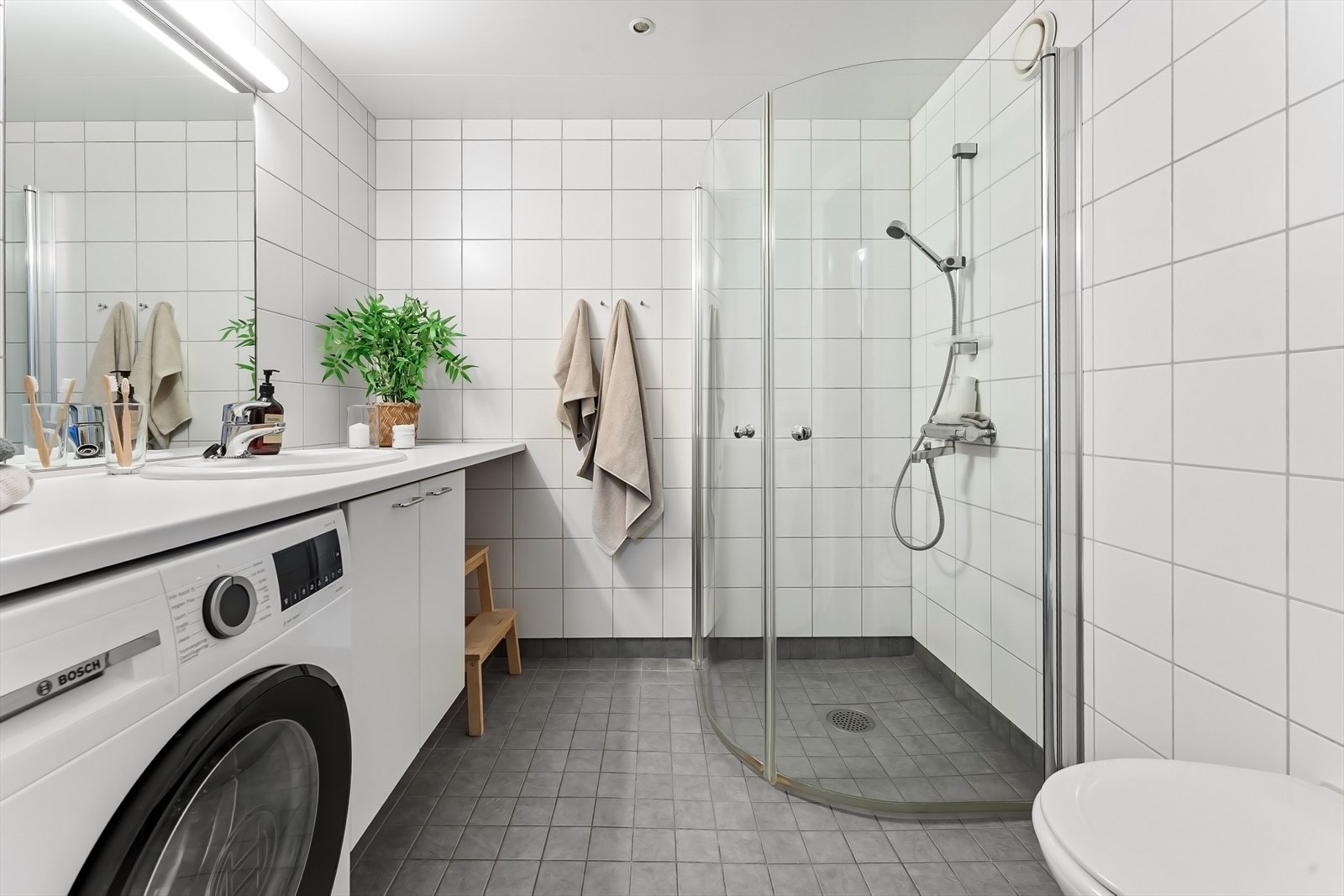 Romslig og delikat bad med praktisk opplegg for vaskemaskin og tørketrommel. Galleribilde