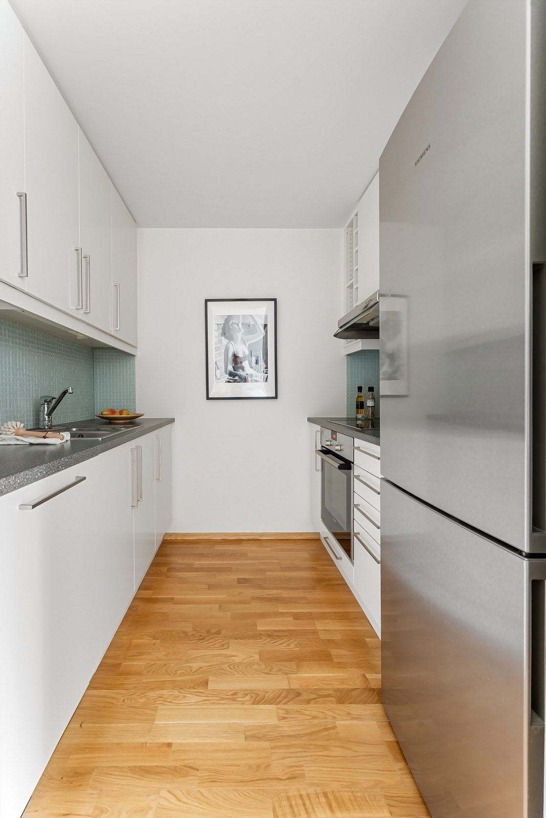 Moderne og funksjonelt Sigdal kjøkken med integrerte hvitevarer (frittstående kjøleskap). Galleribilde