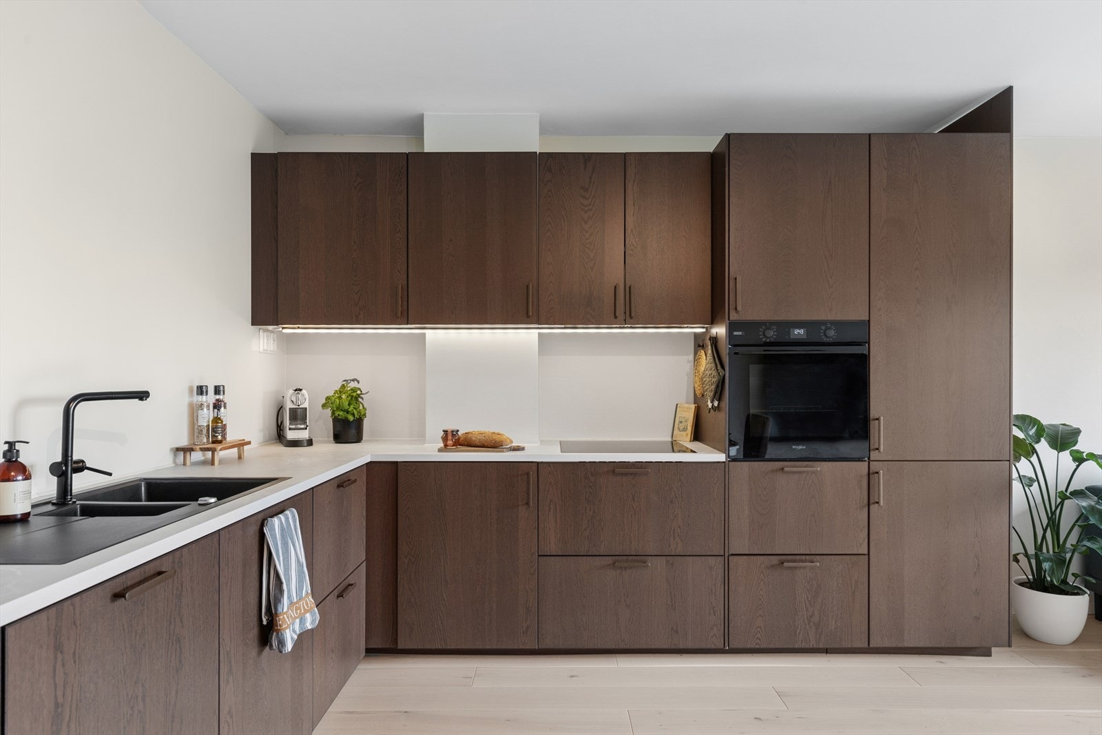 Nytt kjøkken fra IKEA med integrerte hvitevarer utført i 2023. Innredning har glatte mørke eikefronter og hvit laminat benkeplate. Galleribilde