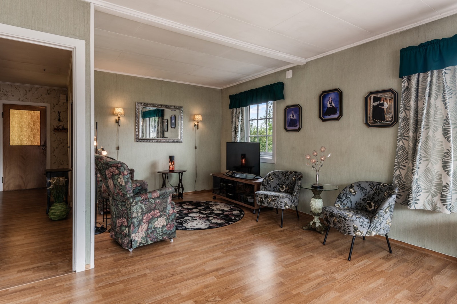 Lys stue med parkettgulv, vegghengte lamper og vindu som slipper inn naturlig lys Galleribilde