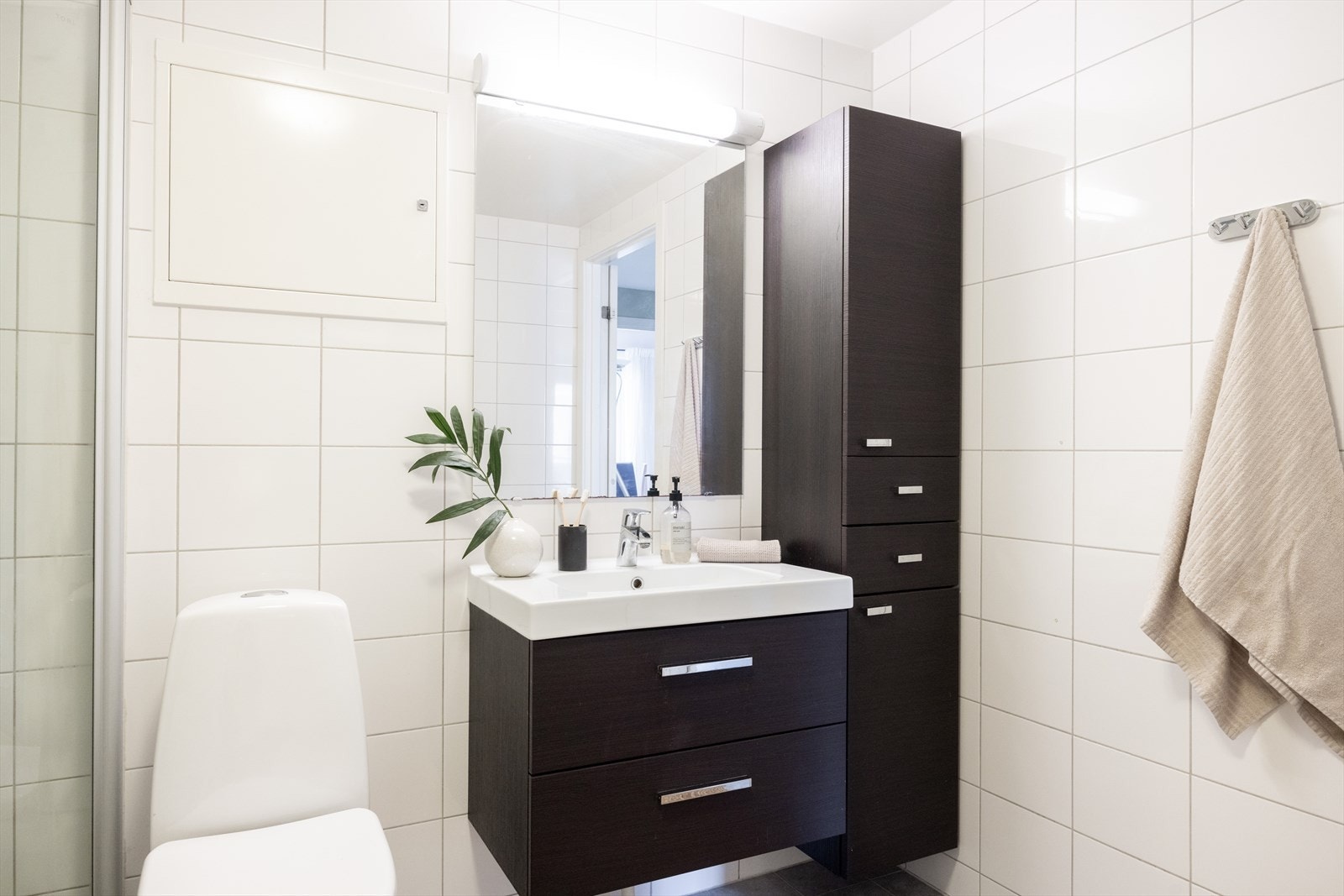 Badet har dusjnisje, baderomsinnredning med speil, gulvstående toalett og opplegg for vaskemaskin. Galleribilde