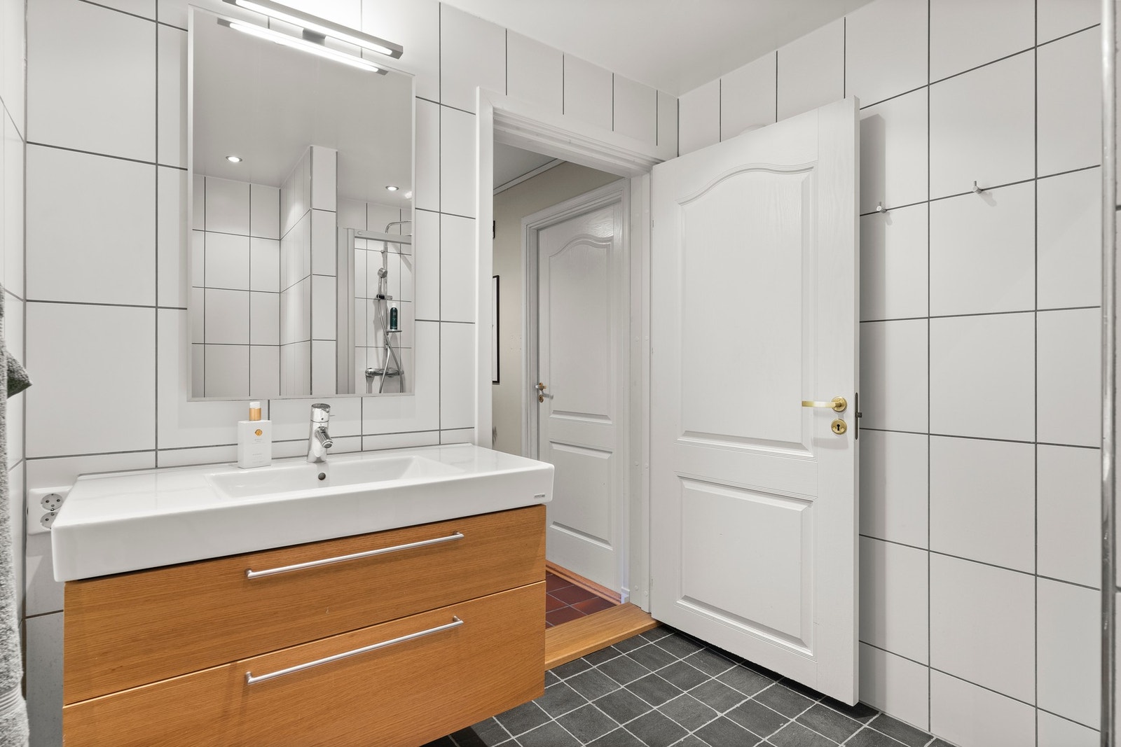 Innredningen består av servantinnredning, speil med lys på vegg over servant og et skjermet dusjhjørne. Galleribilde