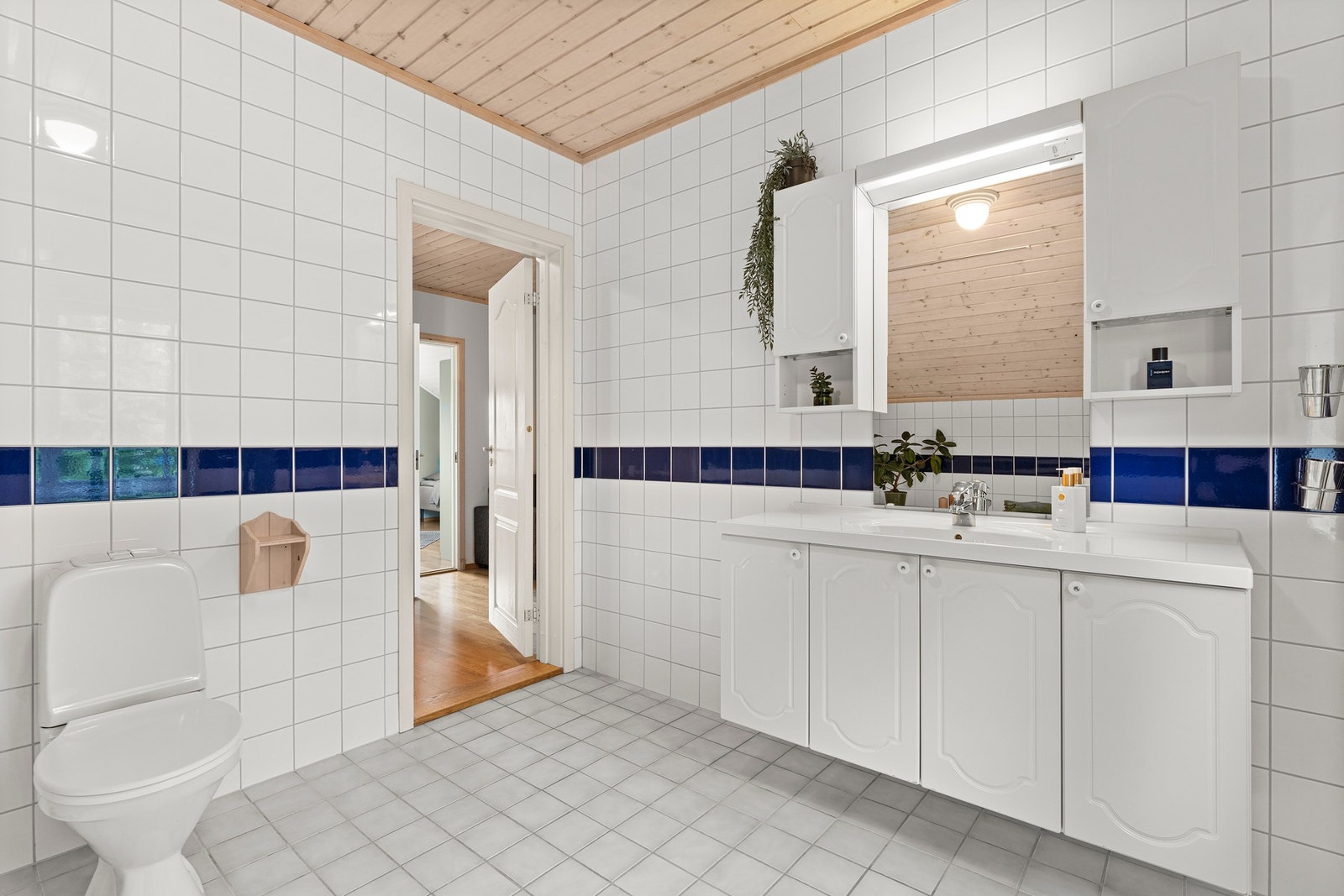 Badet er innredet med servantinnredning, speil på vegg over servant, toalett og badekar. Galleribilde