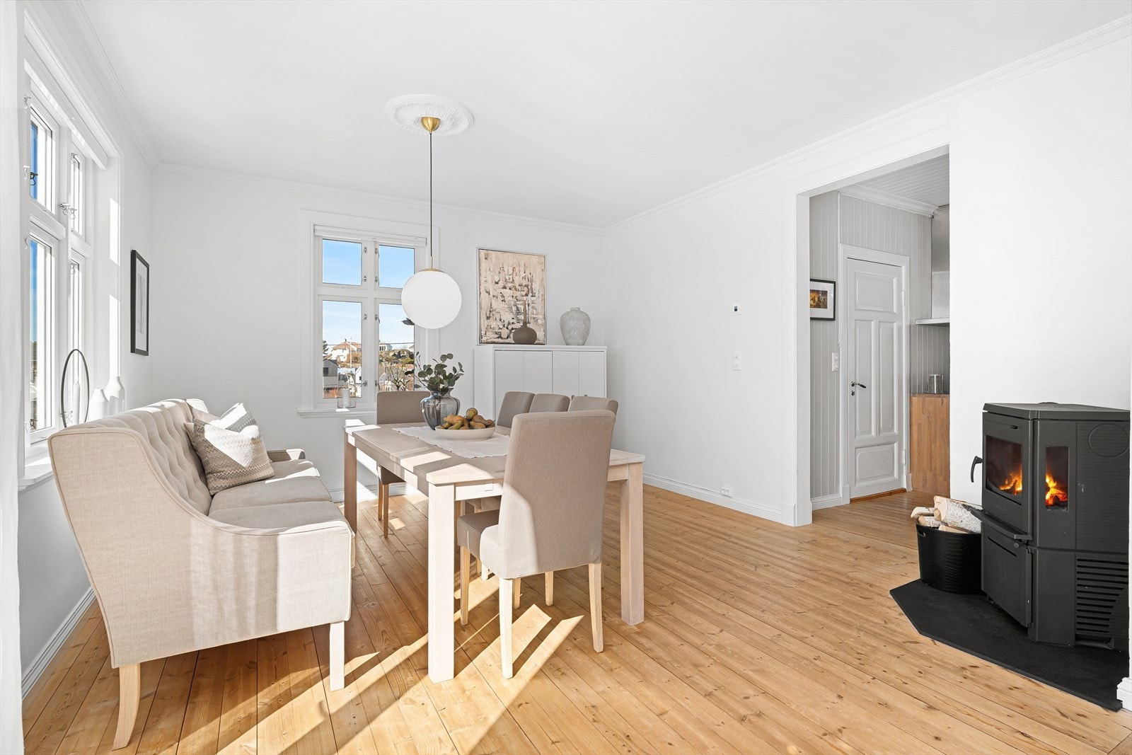 I den store spisestuen/stuen er det svært god plass til et lengre spisebord med tilhørende stoler. Her er det plass til å invitere mange! Legg merke til rosetten i taket over spisestuen, samt vedovnen som gir godt med varme på kaldere dager. Galleribilde