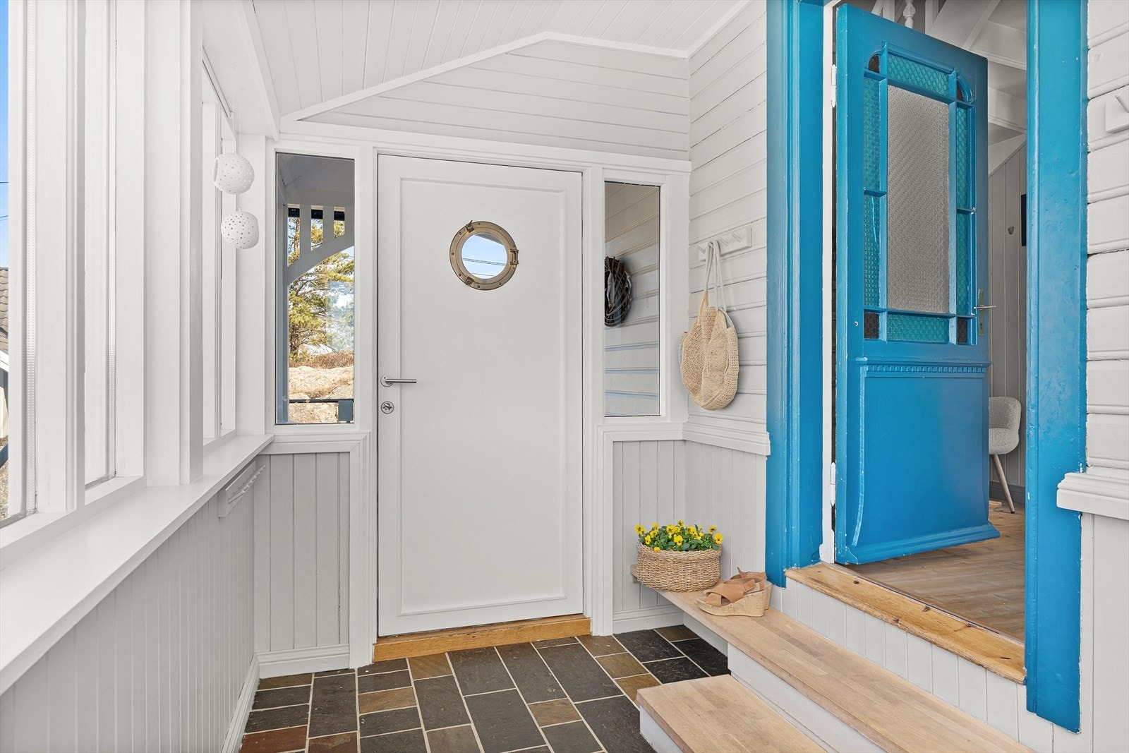 I vindfanget er det skiferfliser på gulvet med varmekabler. Den eldre inngangsdøren er beholdt og vedlikeholdt. Legg merke til detaljene og glassene på den blå inngangsdøren. Galleribilde