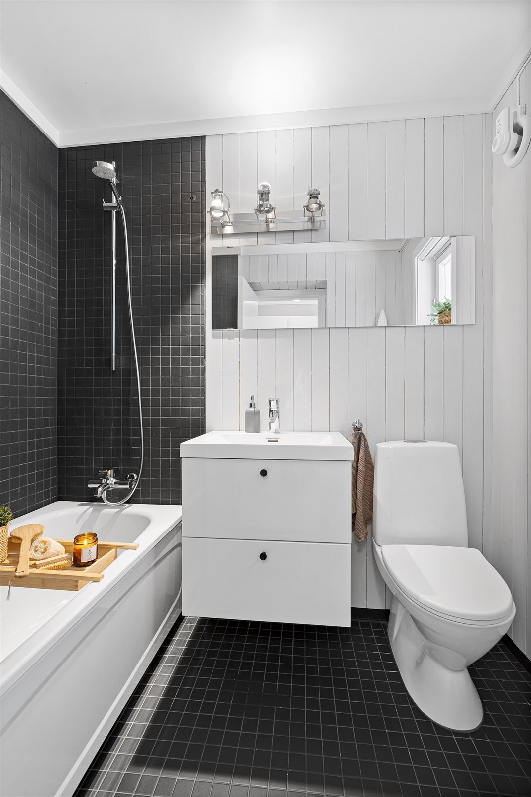 Vegg i vegg med vaskerommet finner du dette badet som ble pusset opp i 2013. Det har fliser på gulv, samt i dusjsonen og inneholder et badekar/dusj, nyere baderomsinnredning med speil over og toalett. Galleribilde