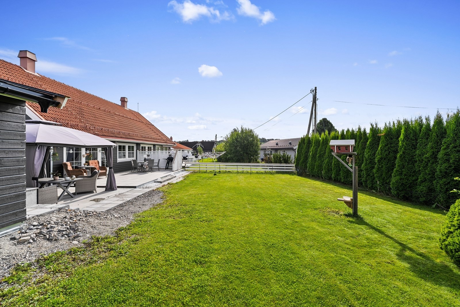 Herlig uteområde med velstelt plen, flat og fin hage med hekk og gjerde mot naboeiendommer. Galleribilde