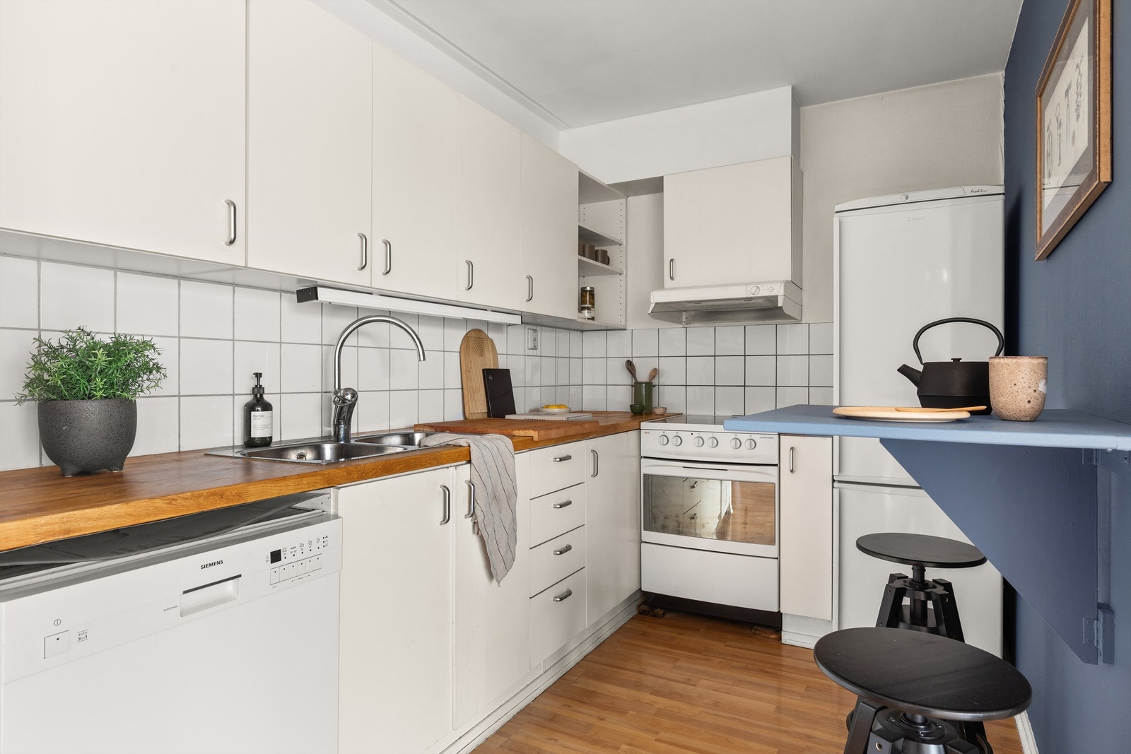 Kjøkkenet er holdt i en praktisk delvis åpen løsning der du får en fin sone for matlagingen. Kjøkkeninnredningen er av glatte fronter og benkeplate i heltre med nedfelt vask. Galleribilde