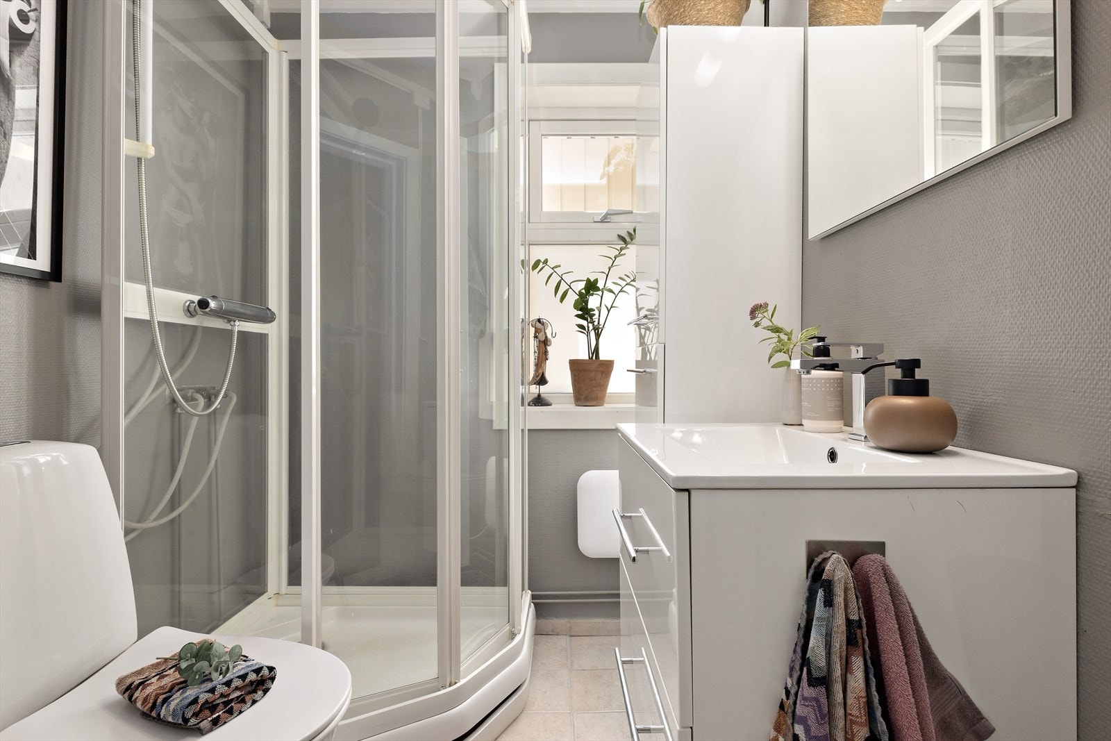 Badet er i gråmalt utførelse og inneholder det du trenger for en god start på dagen. Her nevnes moderne innredning, dusjkabinett og gulvmontert toalett. I gulvet er det er det varmekabler. Galleribilde