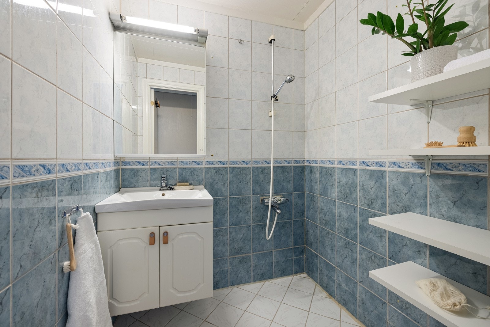 Badet i 1. etasjen er helfliset og har varmekabler i gulv samt baderomsinnredning med nedfelt servant og dusjhjørne. Galleribilde