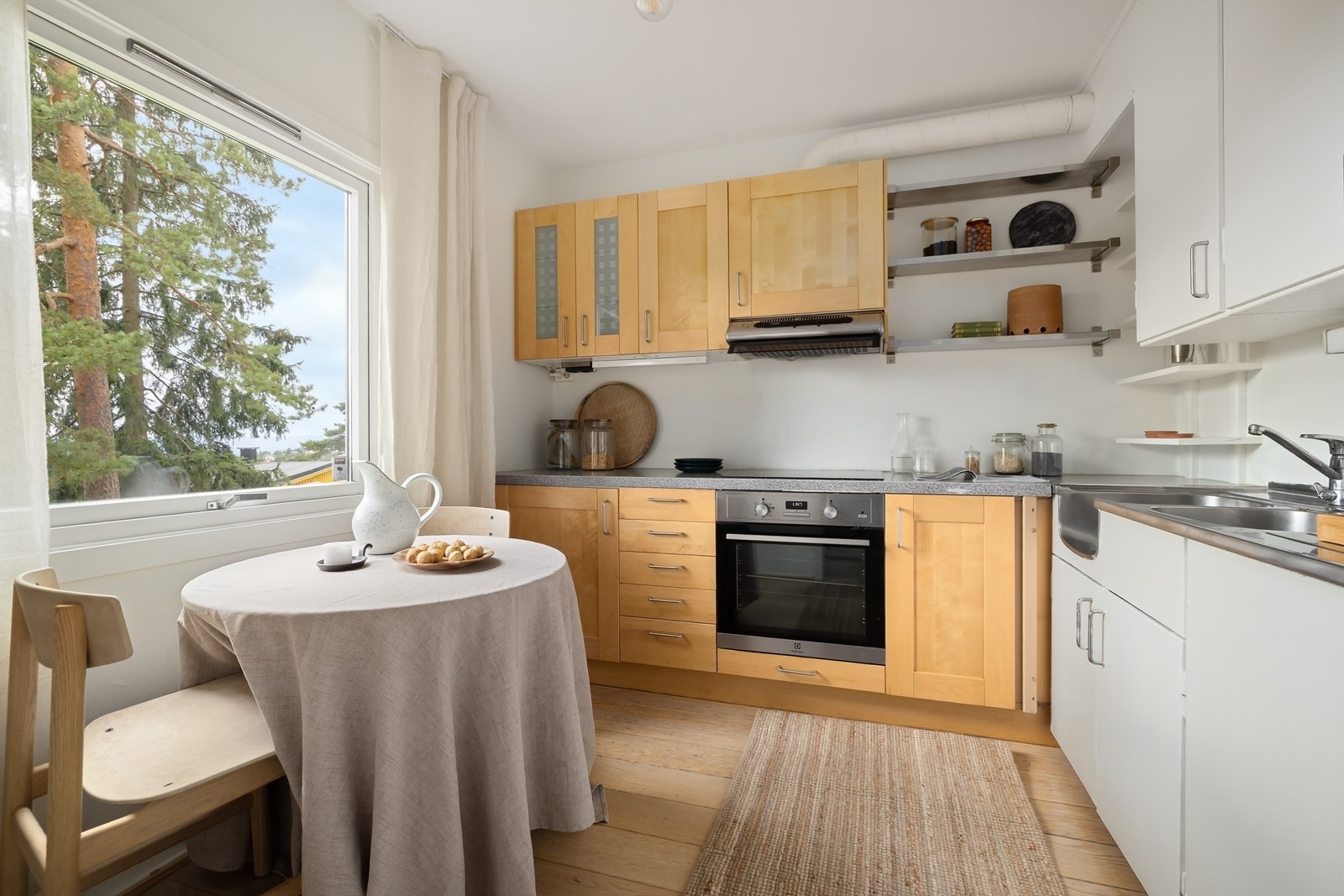 Eldre men funksjonelt kjøkken med hvite og trefargede fronter, rustfri oppvaskbenk med utslagsvask, oppvaskkum og ett-greps armatur Galleribilde