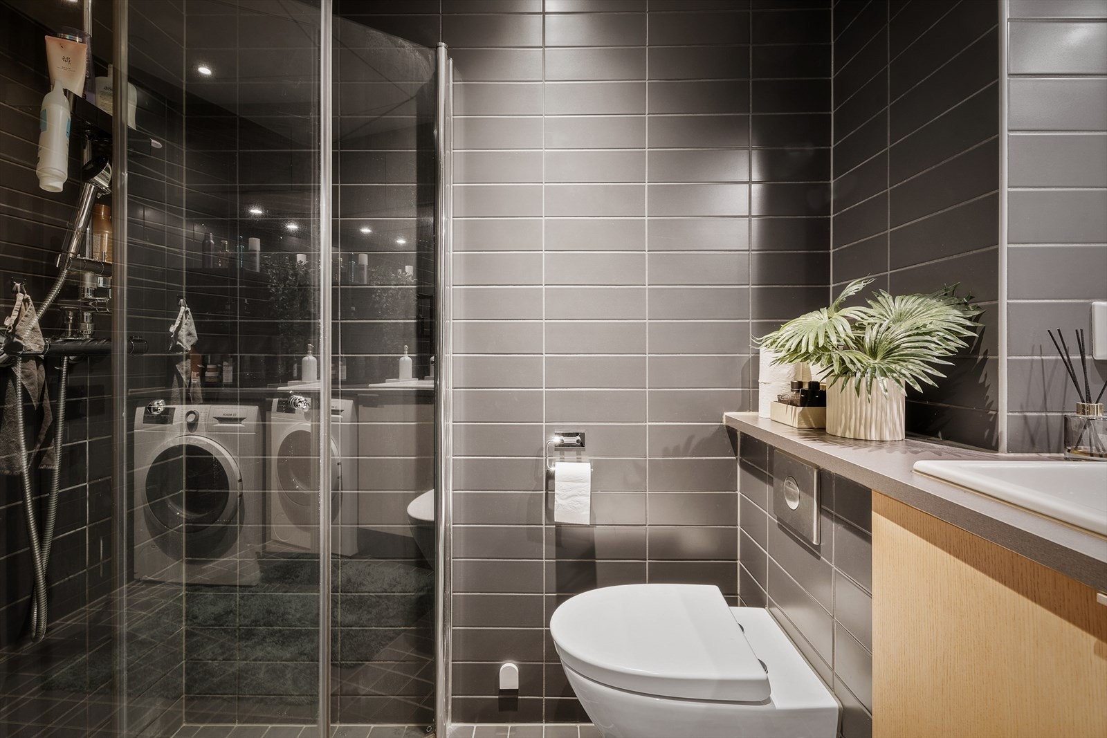 Dusjhjørne med glassdører og vegghengt toalett. Lekre materialvalg og farger. Galleribilde