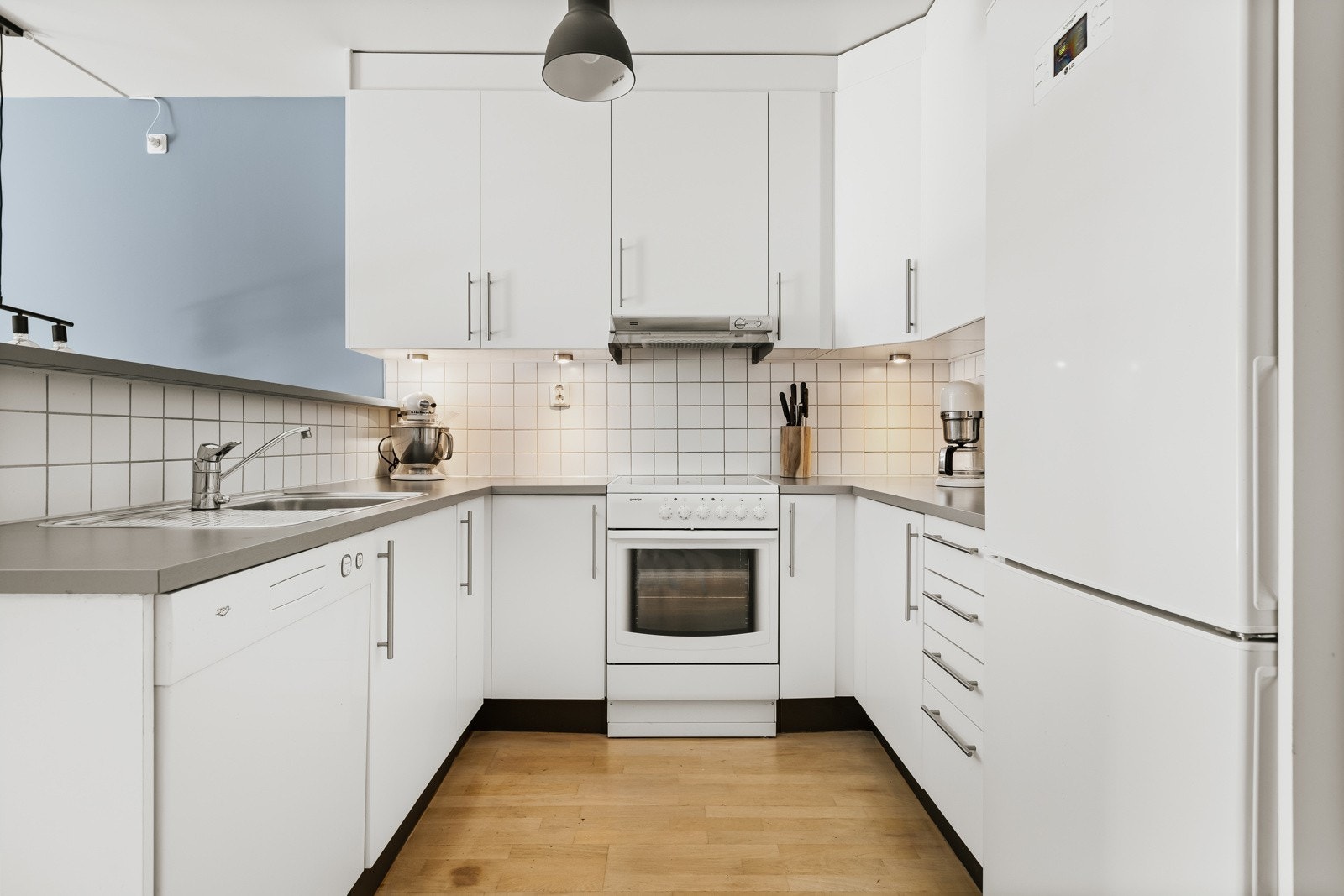 Kjøkkenet inneholder hvitevarer som oppvaskmaskin, kombiskap og komfyr med steketopp Galleribilde