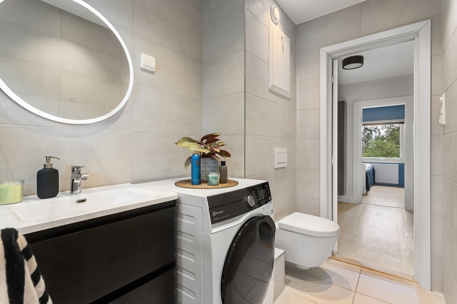 Badet er innredet med vegghengt toalett, dusj med en fastmontert dusjvegg, servant i skuffeinnredning samt opplegg for vaskemaskin. Galleribilde