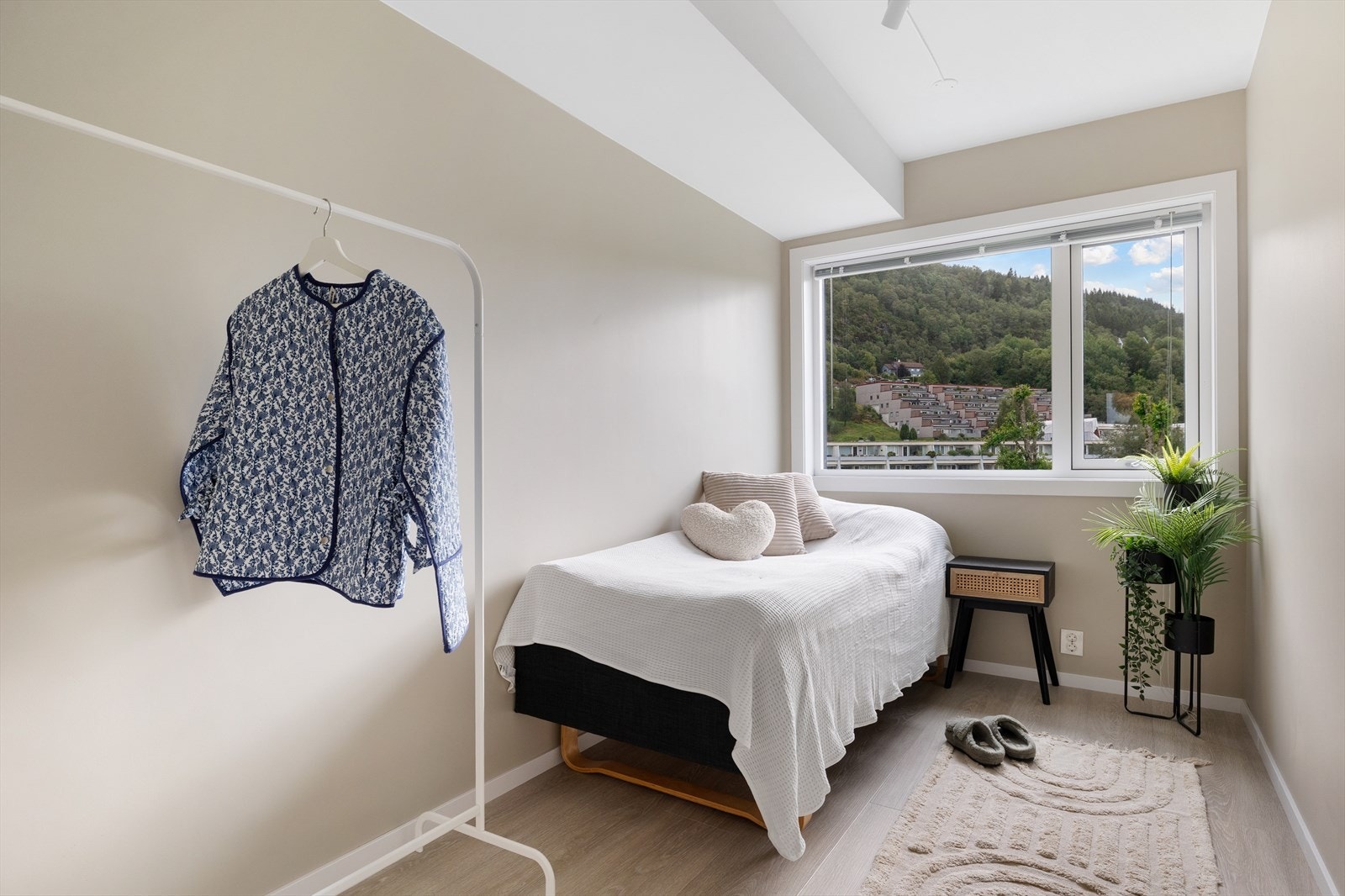 Soverom 2 har vegger malt i en lys beige tone, og et stort vindu som slipper inn rikelig med naturlig lys Galleribilde