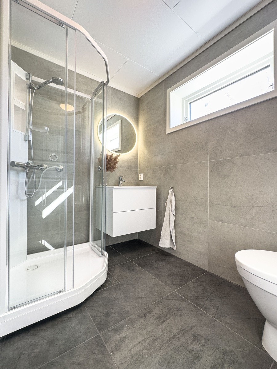 I første etasje finner du et totalrenovert bad som er utstyrt med toalett, vask med oppbevaring, dusj og et rålekkert speil Galleribilde