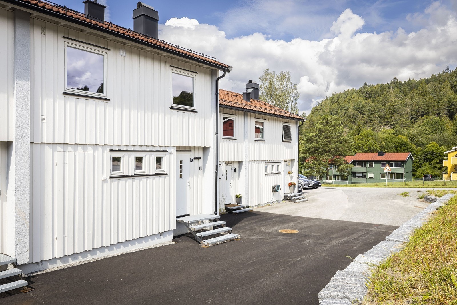 Boligens inngangsparti er asfaltert og det er egen parkeringsplass på siden av bygget Galleribilde