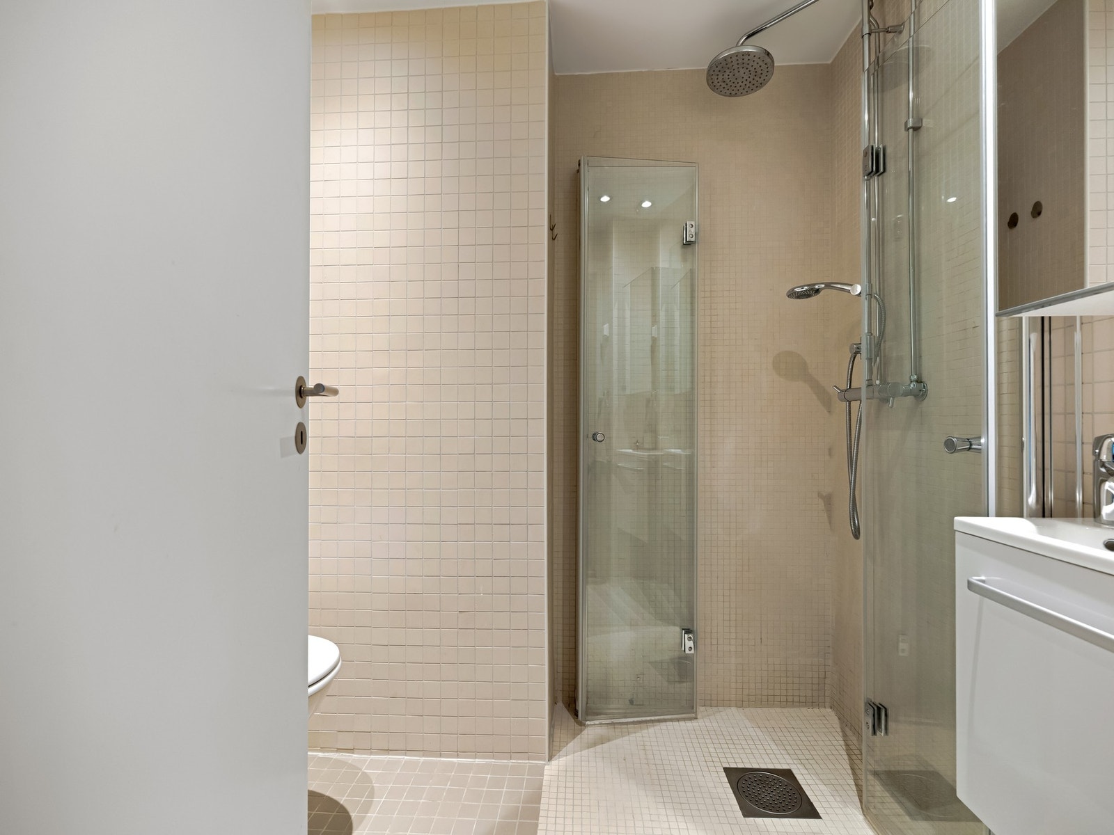 Lyst og fint flislagt bad fra 2006 med lune varmekabler i gulv og downlights i tak. Galleribilde