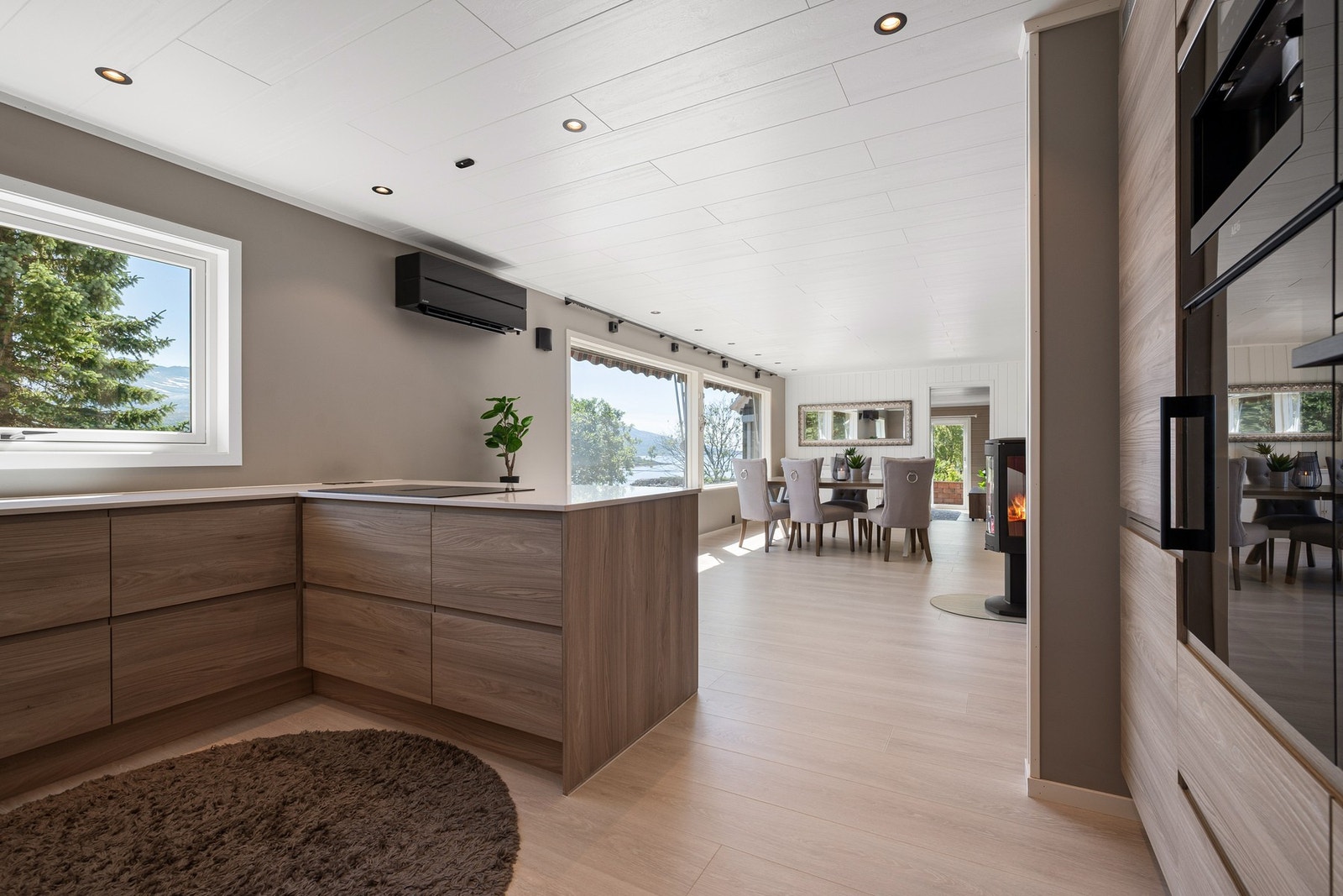 Åpen løsning mellom spisestue og kjøkken. Den sorte Mitsubishi varmepumpen fra 2022 sørger for stabil temperatur året rundt Galleribilde