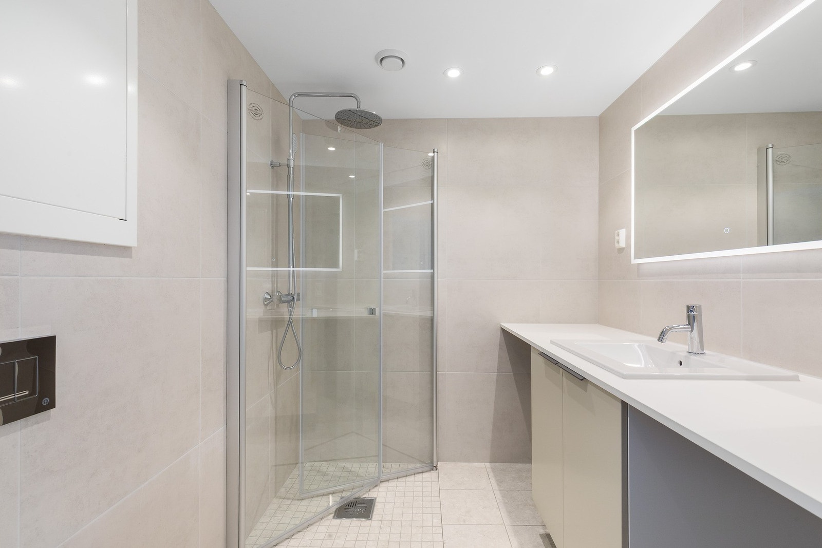 Badet på 4 kvm har lyse fine fliser, moderne speil med lys og en stor benkeplate med plass til vaskemaskin under Galleribilde